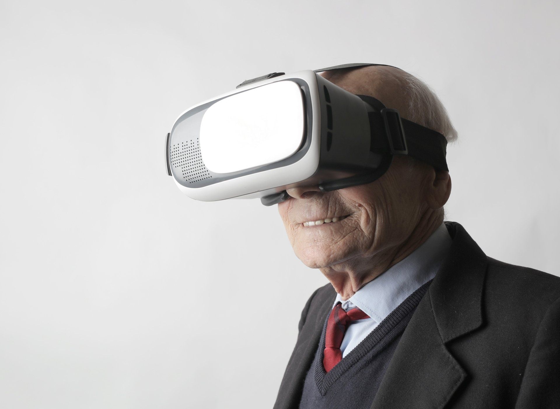 An elderly man is wearing a virtual reality headset.
