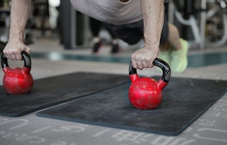 A man is doing push ups with a kettlebell in a gym for rehab therapy in Littleton, CO.