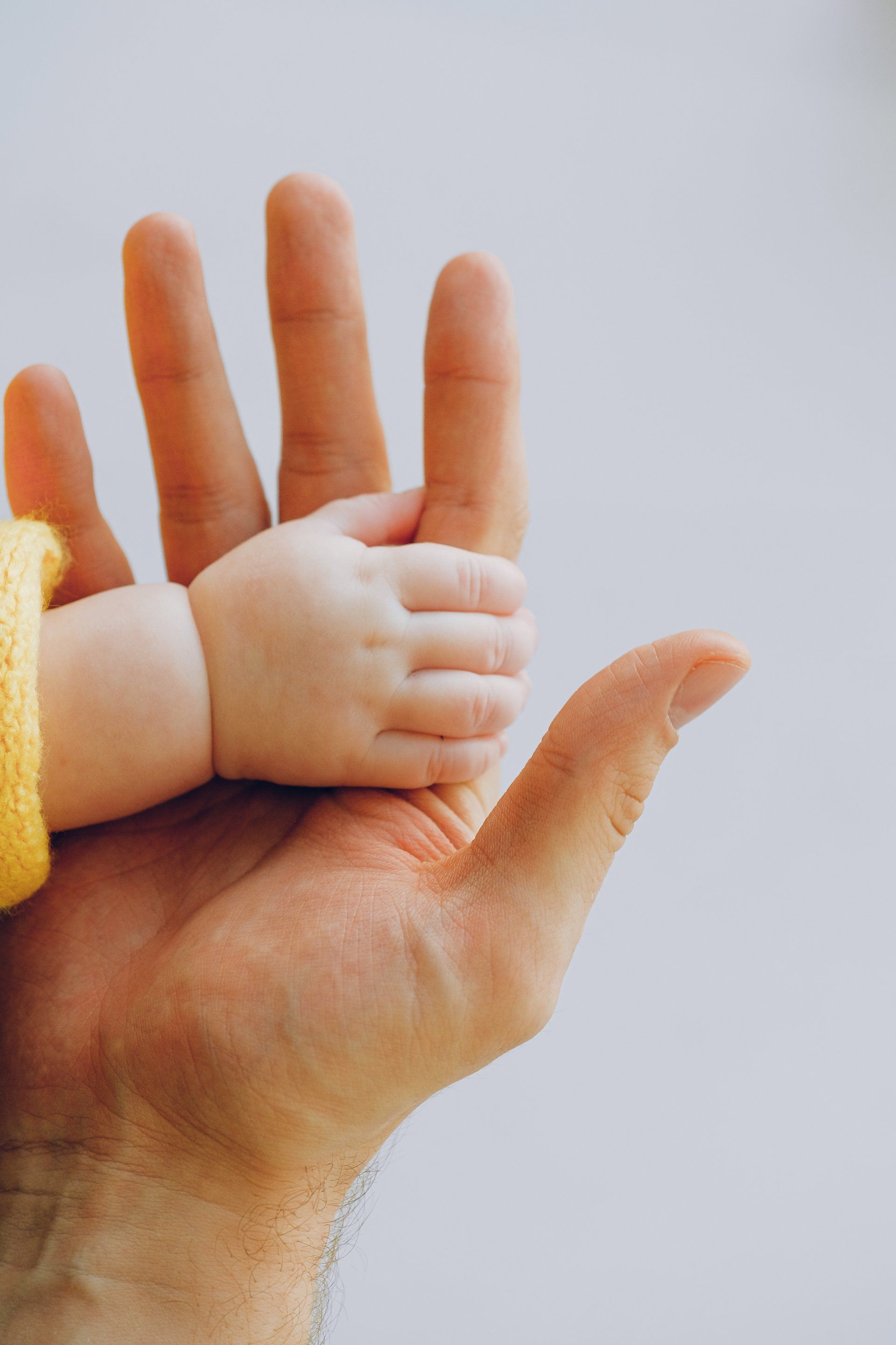 A man is holding a baby 's hand in his hand.of Martin Quiroz