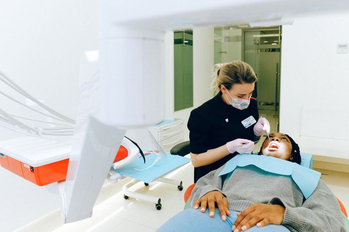 A woman is getting her teeth examined by a dentist in a dental office.