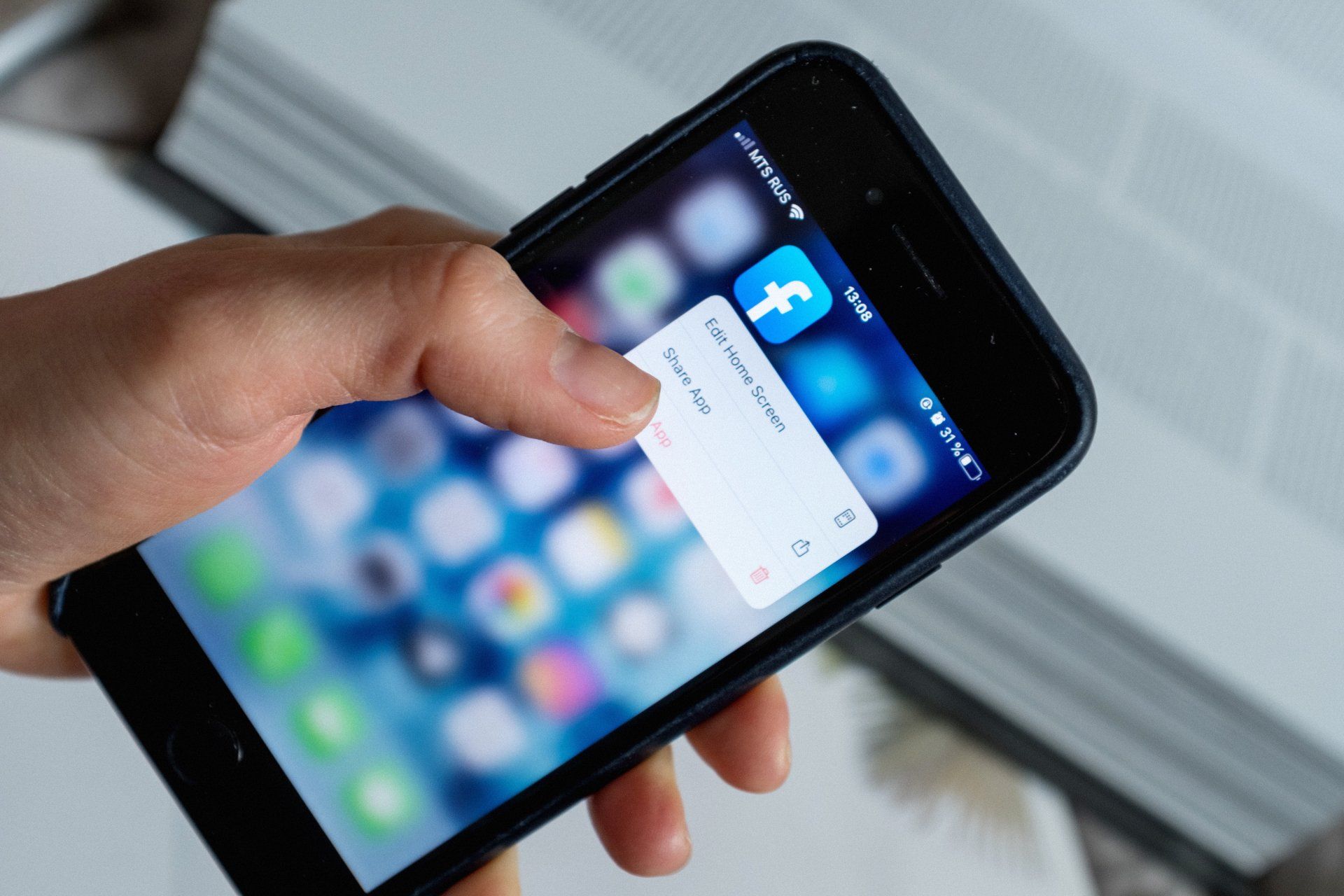 una persona tiene in mano uno smartphone con l' app facebook sullo schermo .