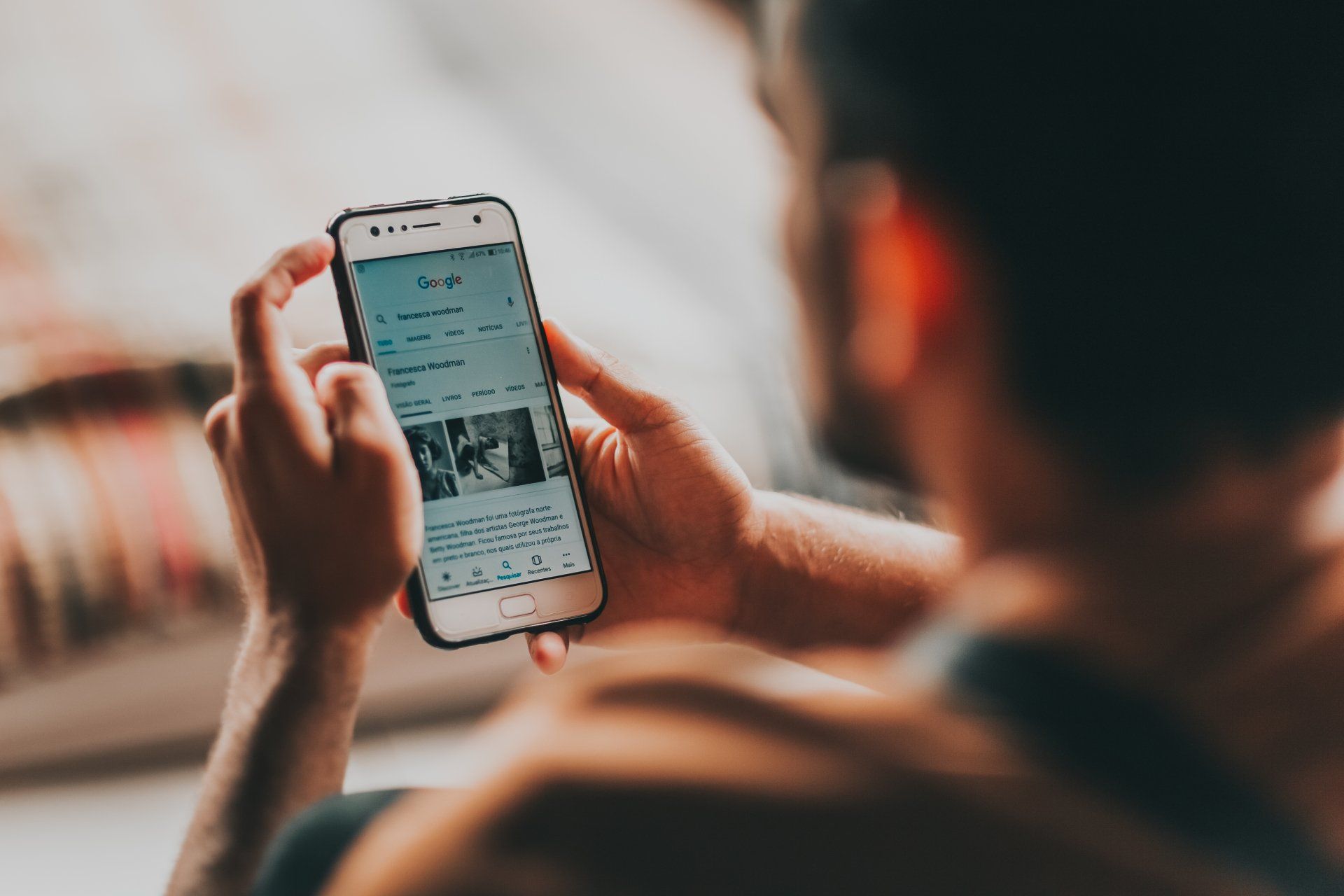 A man is using a cell phone while sitting on a couch.