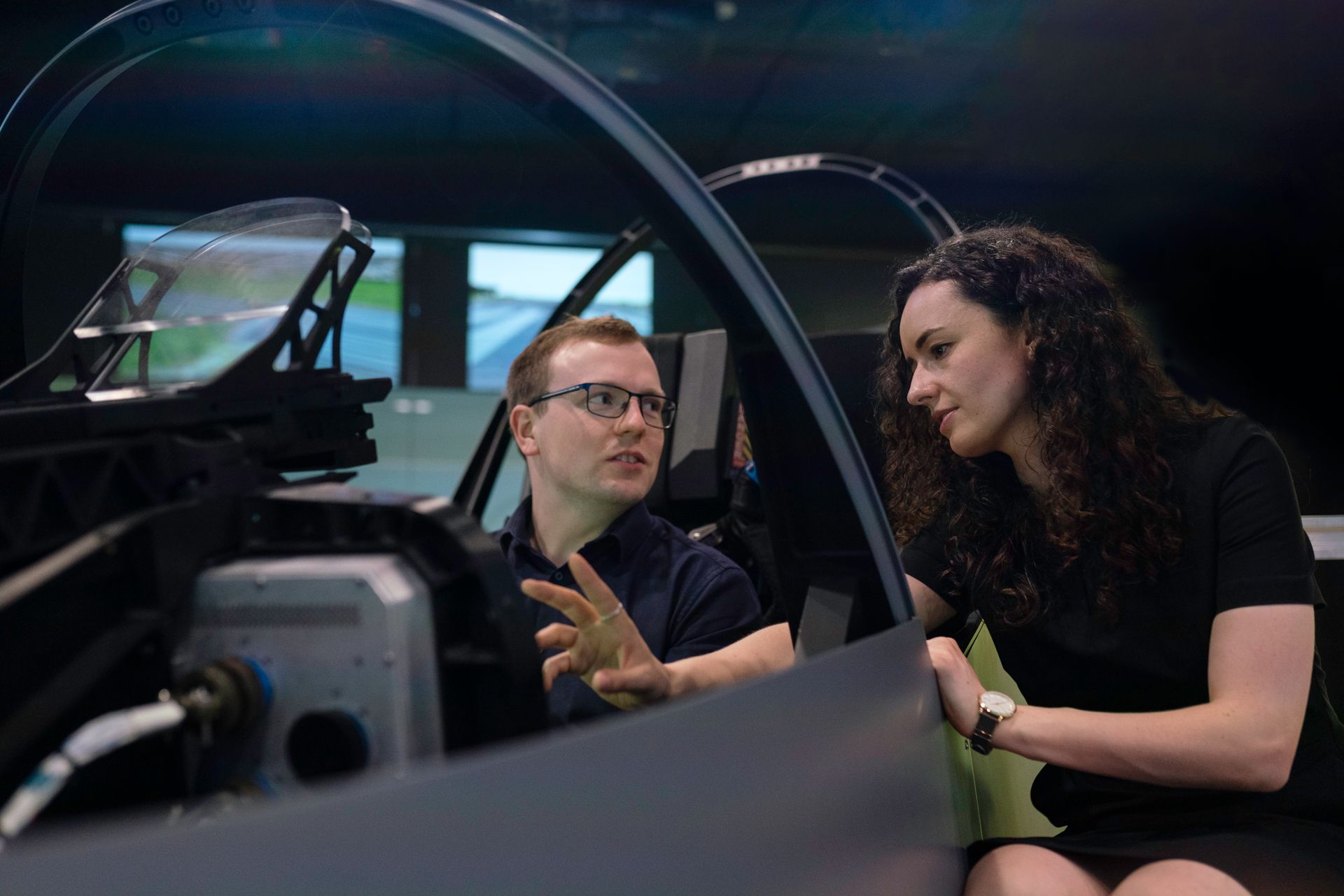 Flight instructor teaching student pilot in full-motion flight simulator during training.