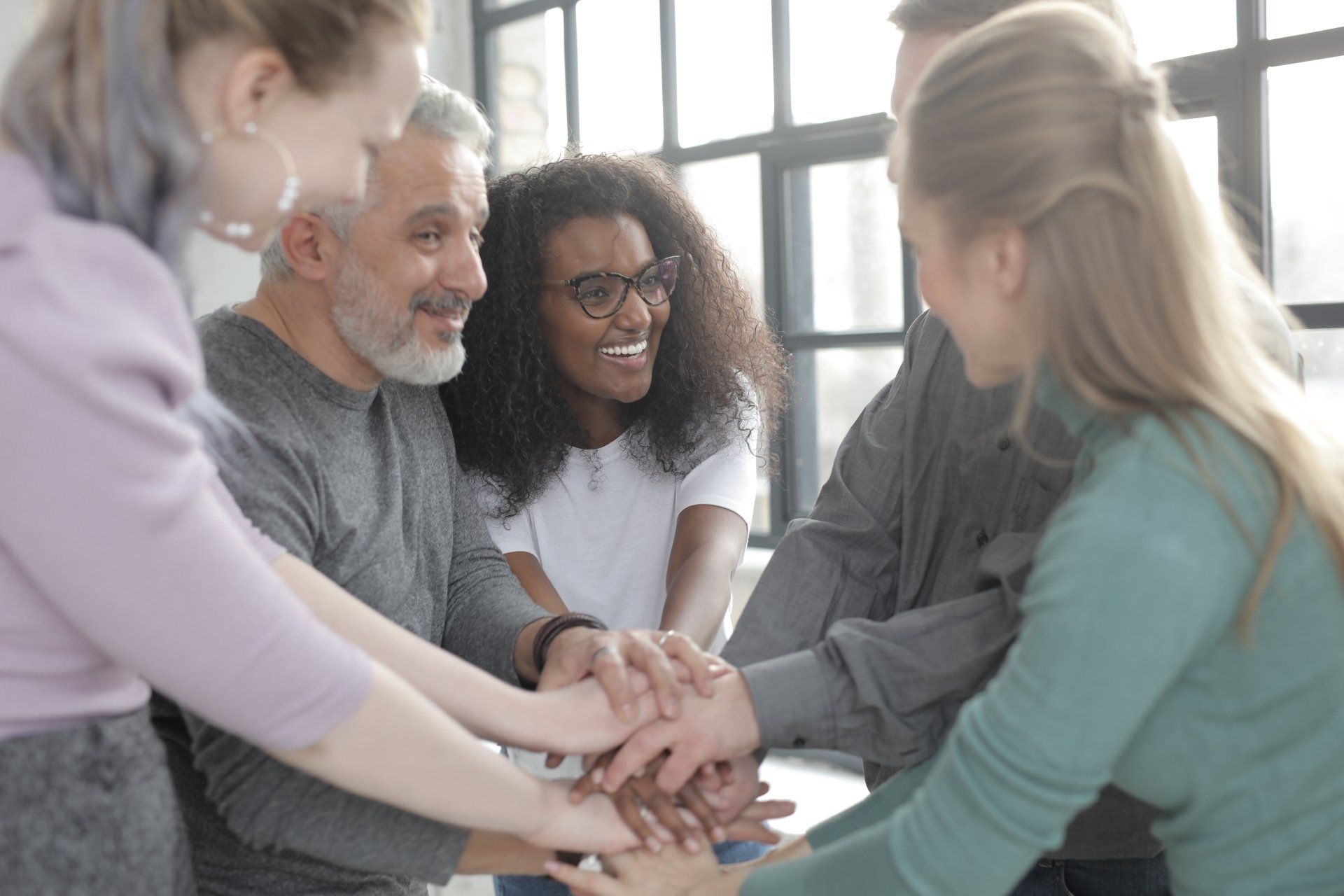 A group of people are putting their hands together in a huddle.