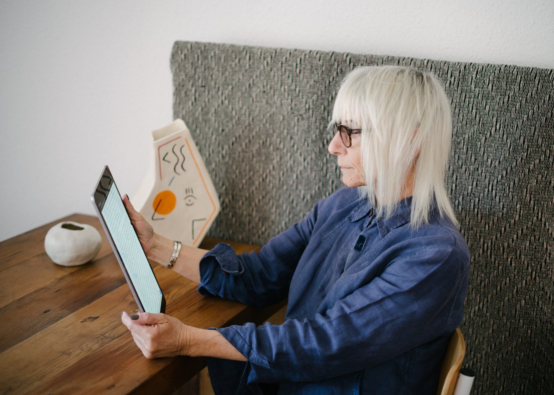 woman sitting at a table using tablet