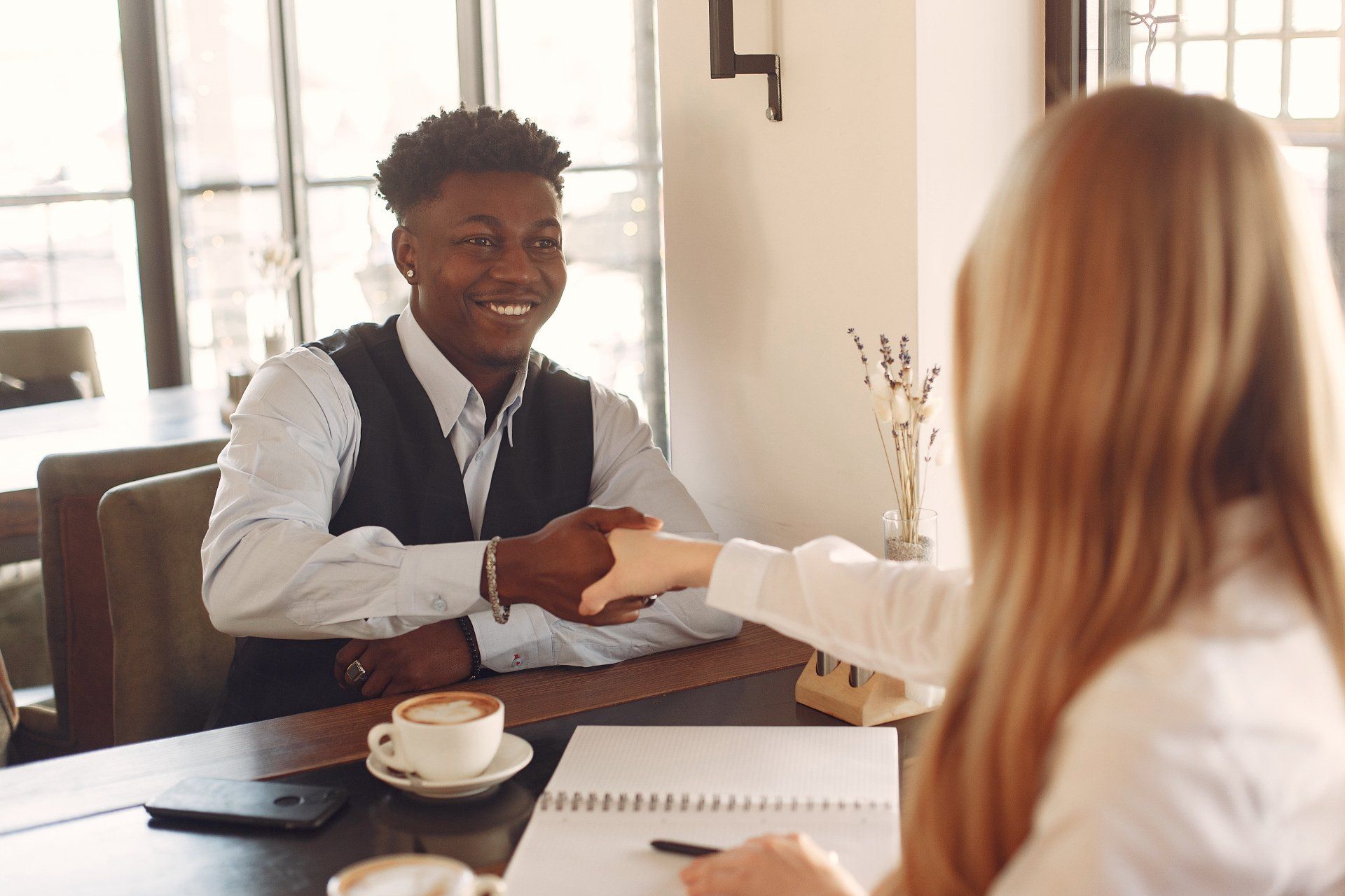 A man and a woman are shaking hands during a job interview.