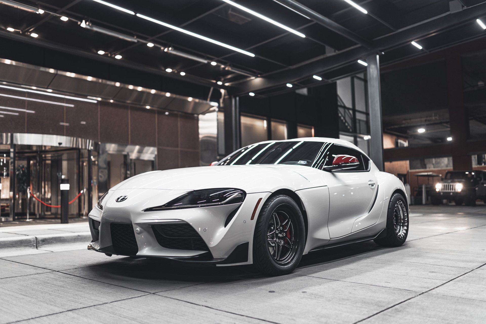 A white sports car is parked in front of a building.