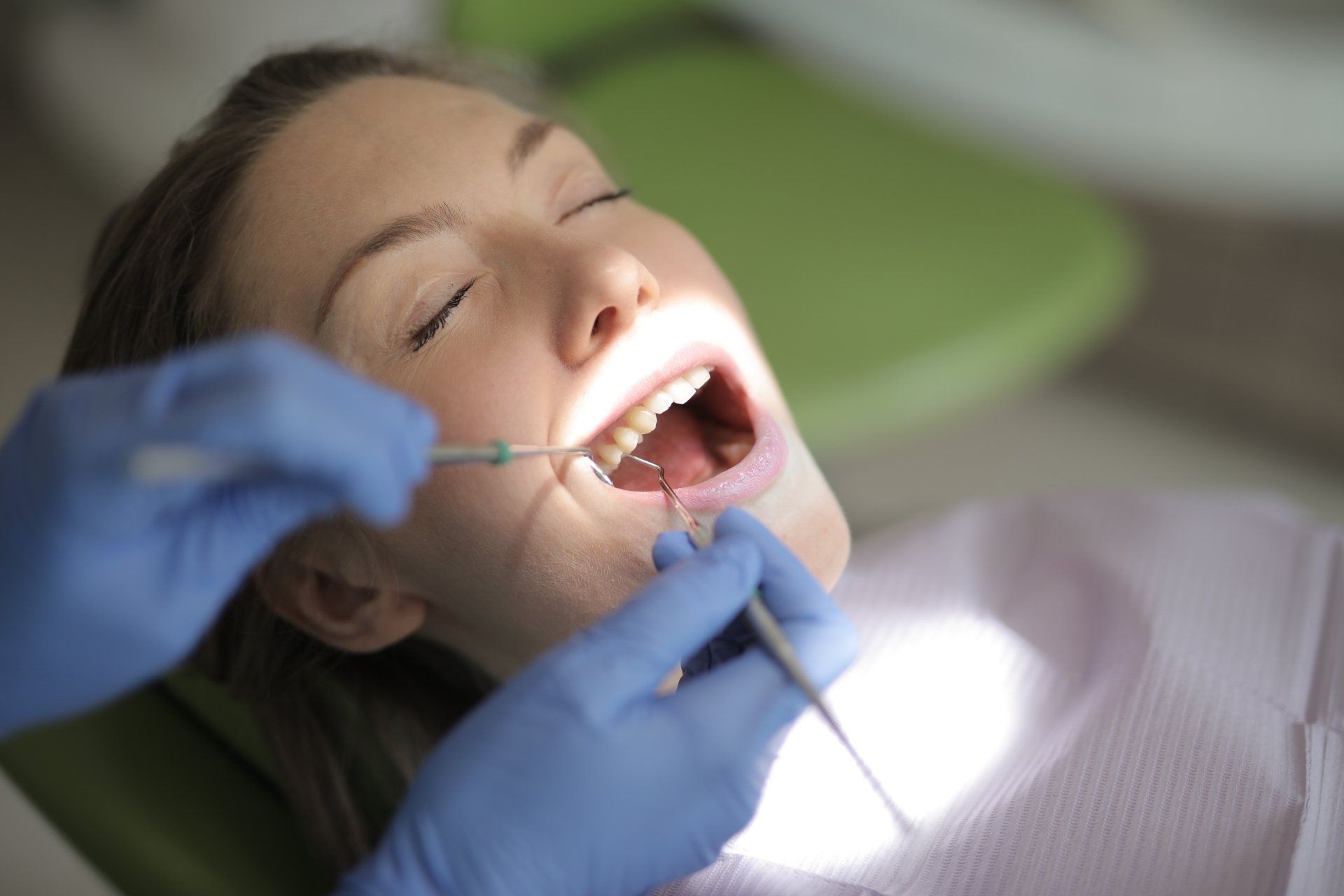 A woman is getting her teeth examined by a dentist.