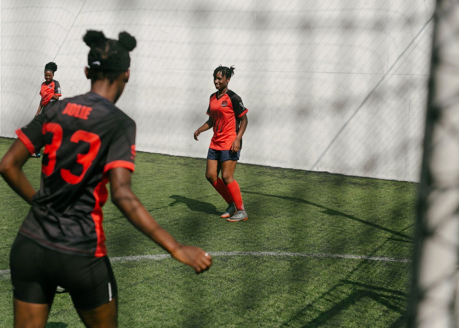 2 girls playing football on an artificial pitch