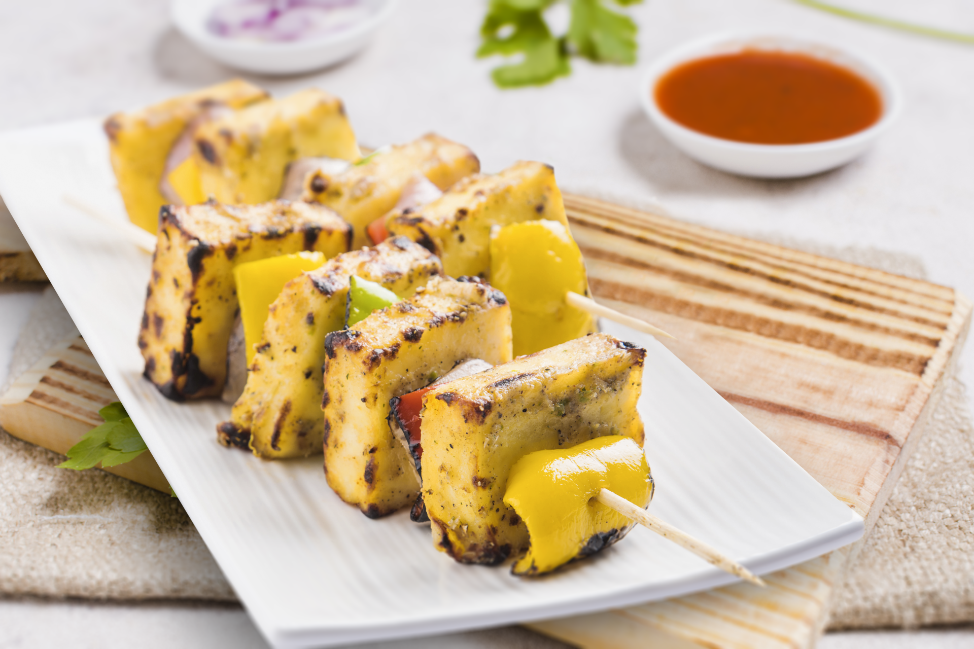 A white plate topped with cheese and vegetables on skewers