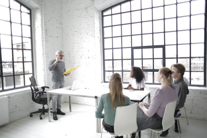 A man is giving a presentation to a group of people sitting around a table.