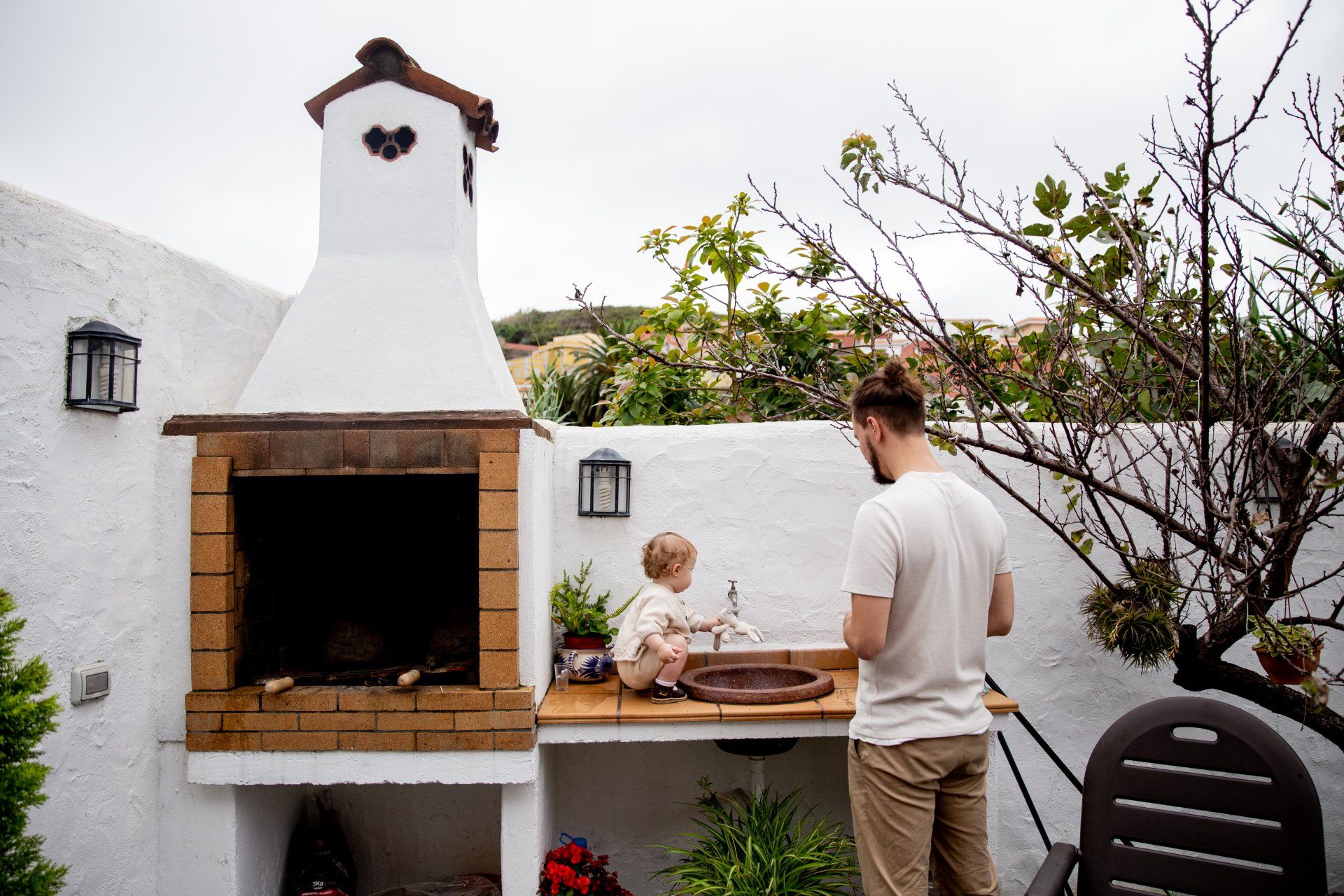 A man and a child are standing in front of a barbecue grill.