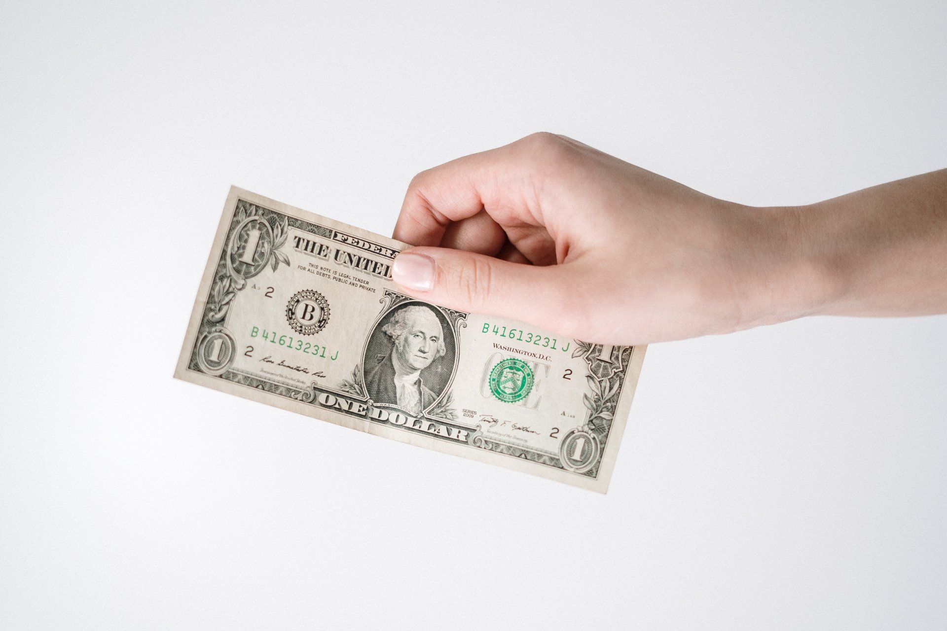 hand holding out a one dollar bill