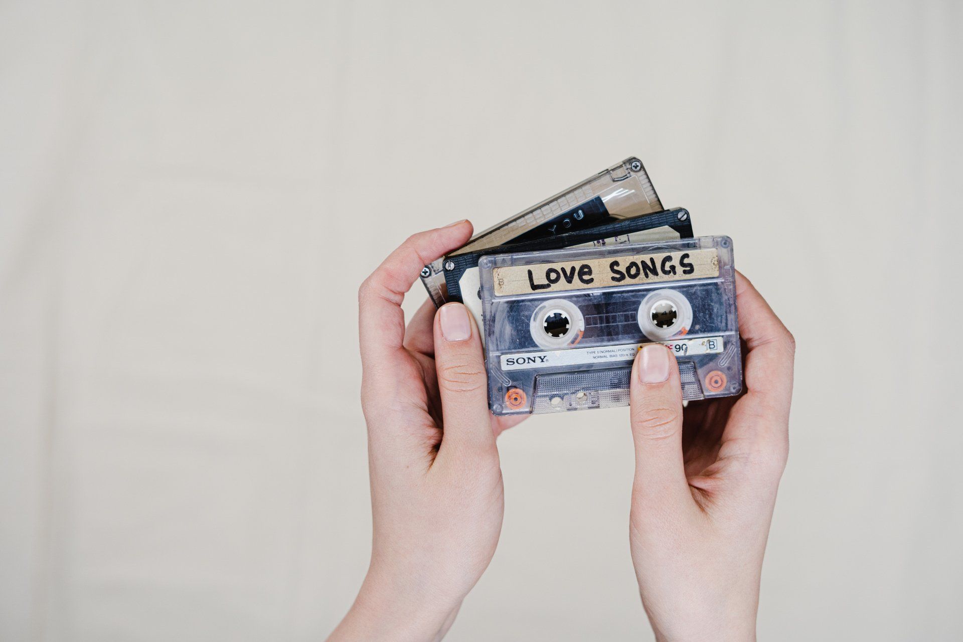 A person is holding a cassette tape with love songs on it.