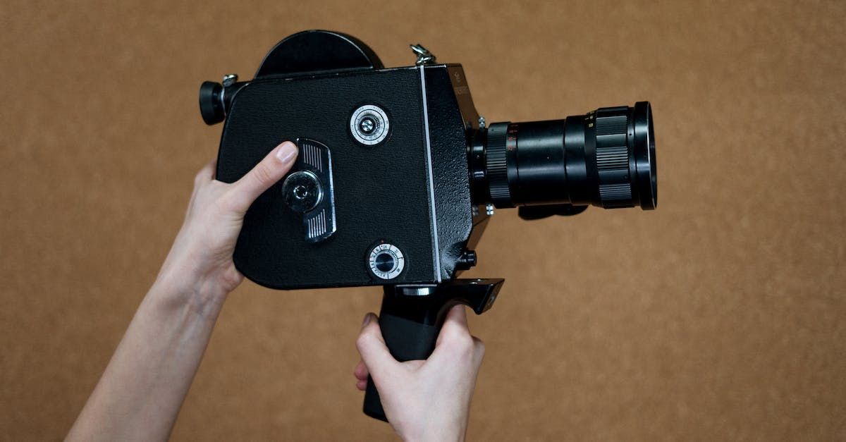 A person is holding a black video camera in their hands.
