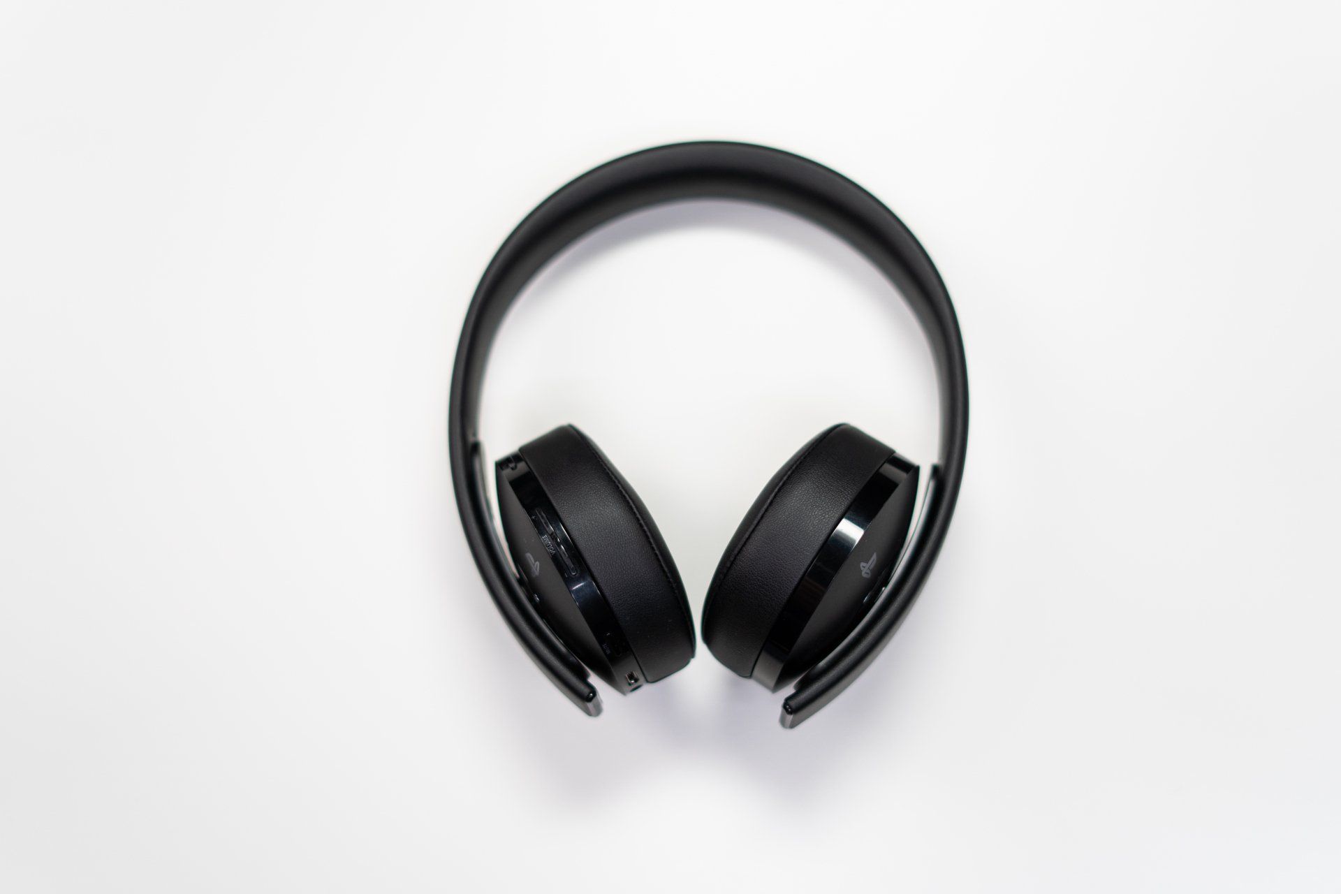 A pair of black headphones are sitting on a white surface.