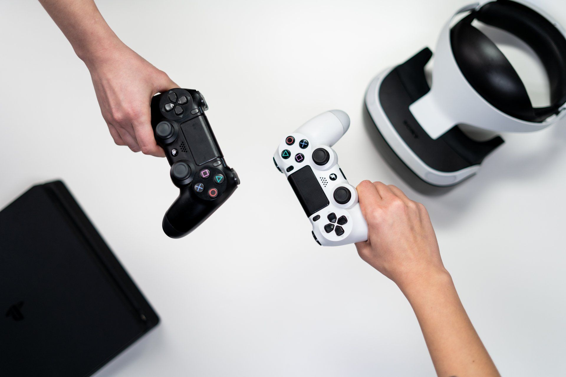 A person is holding a video game controller next to a virtual reality headset.