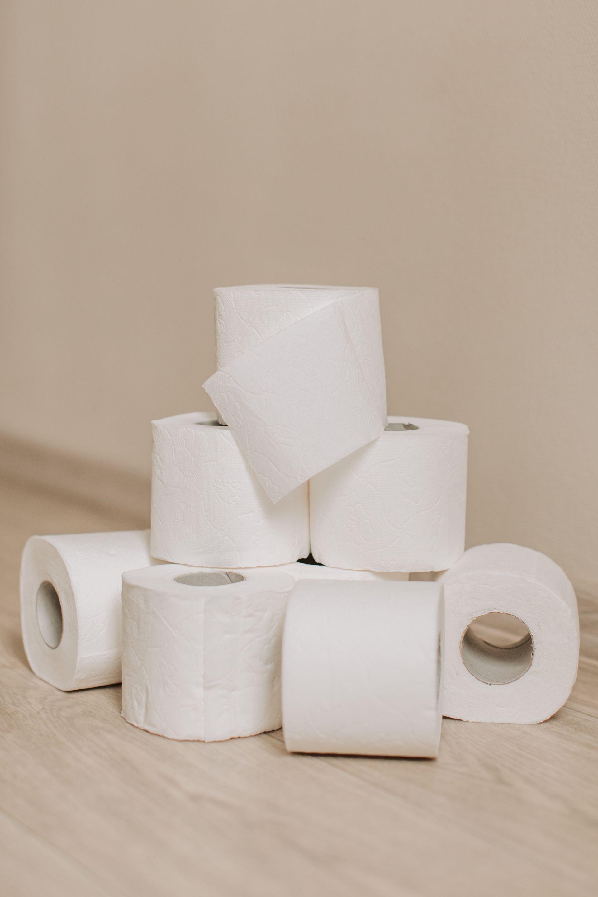 A pile of toilet paper rolls stacked on top of each other on a wooden floor.