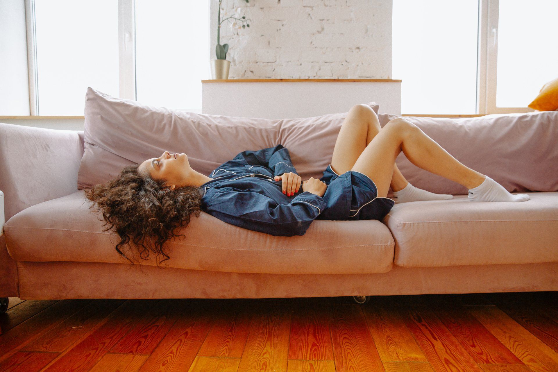 A woman is laying on a couch with her legs crossed.
