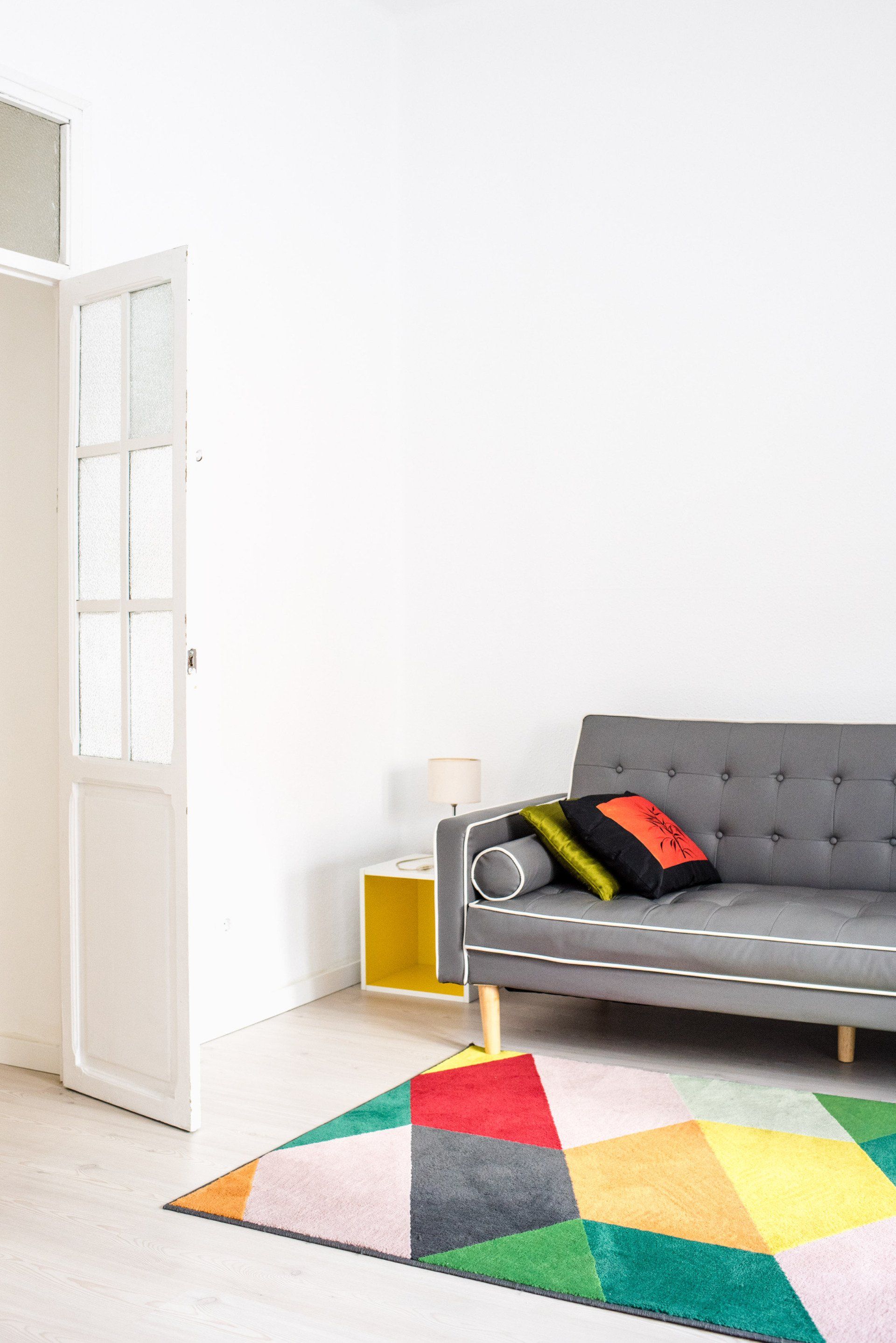 A living room with a couch and a colorful rug.