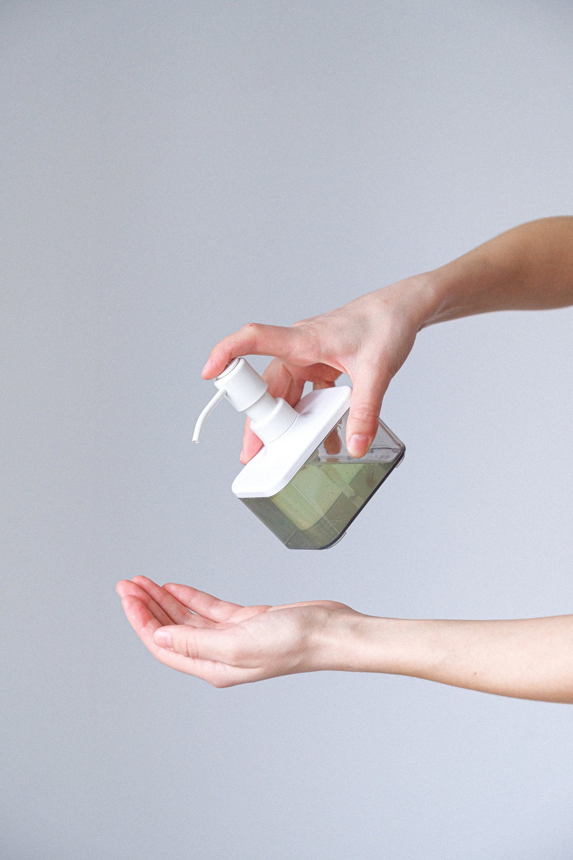 A woman is applying hand sanitizer to another person 's hand.
