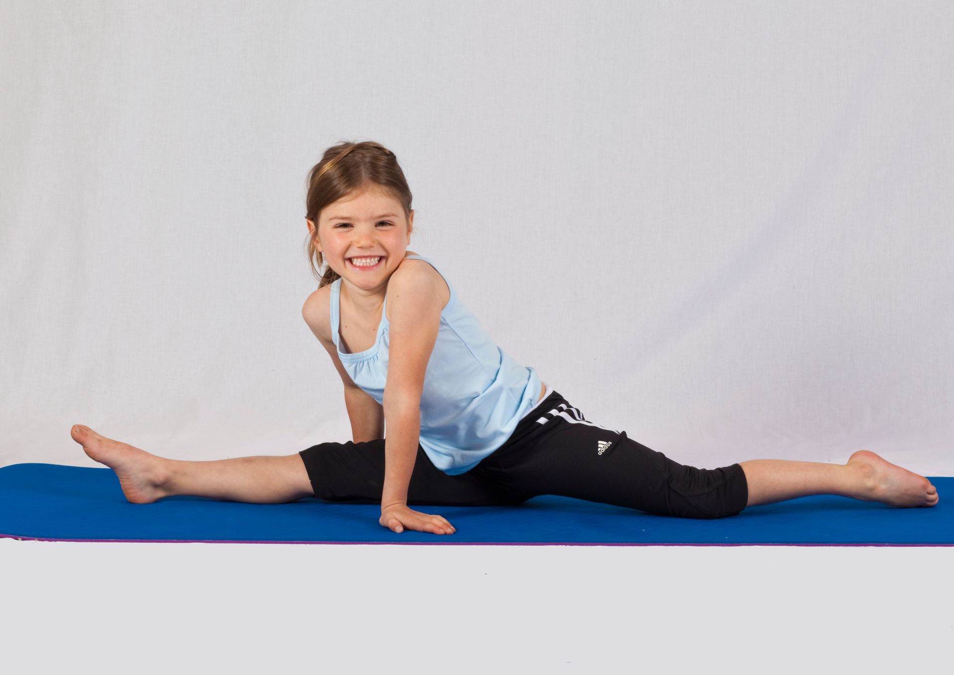 A boy and a girl are jumping over blocks in a gym.