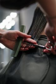 Hairdresser cutting hair with scissors and comb.