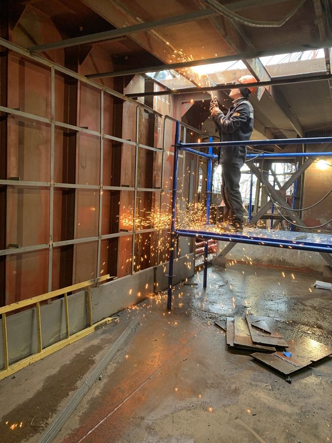 A man is welding a piece of metal on a scaffolding.