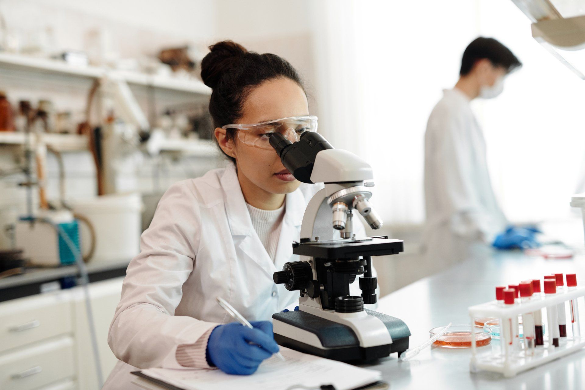 Woman looking through a microscope at samples