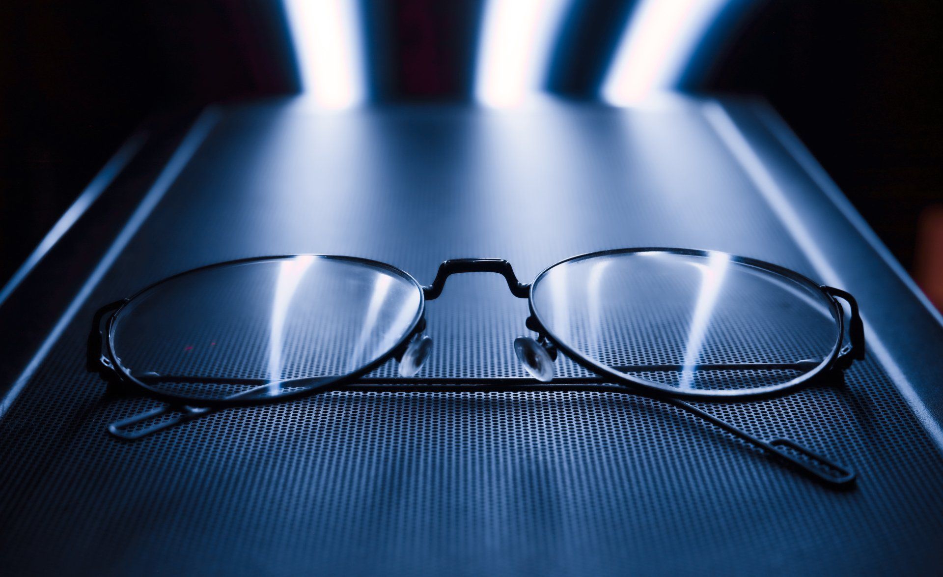 A pair of glasses is sitting on a black surface.