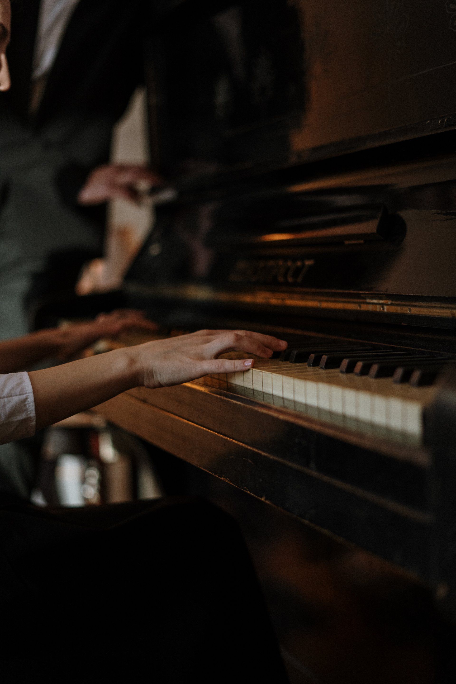 Une personne joue du piano dans une pièce sombre.