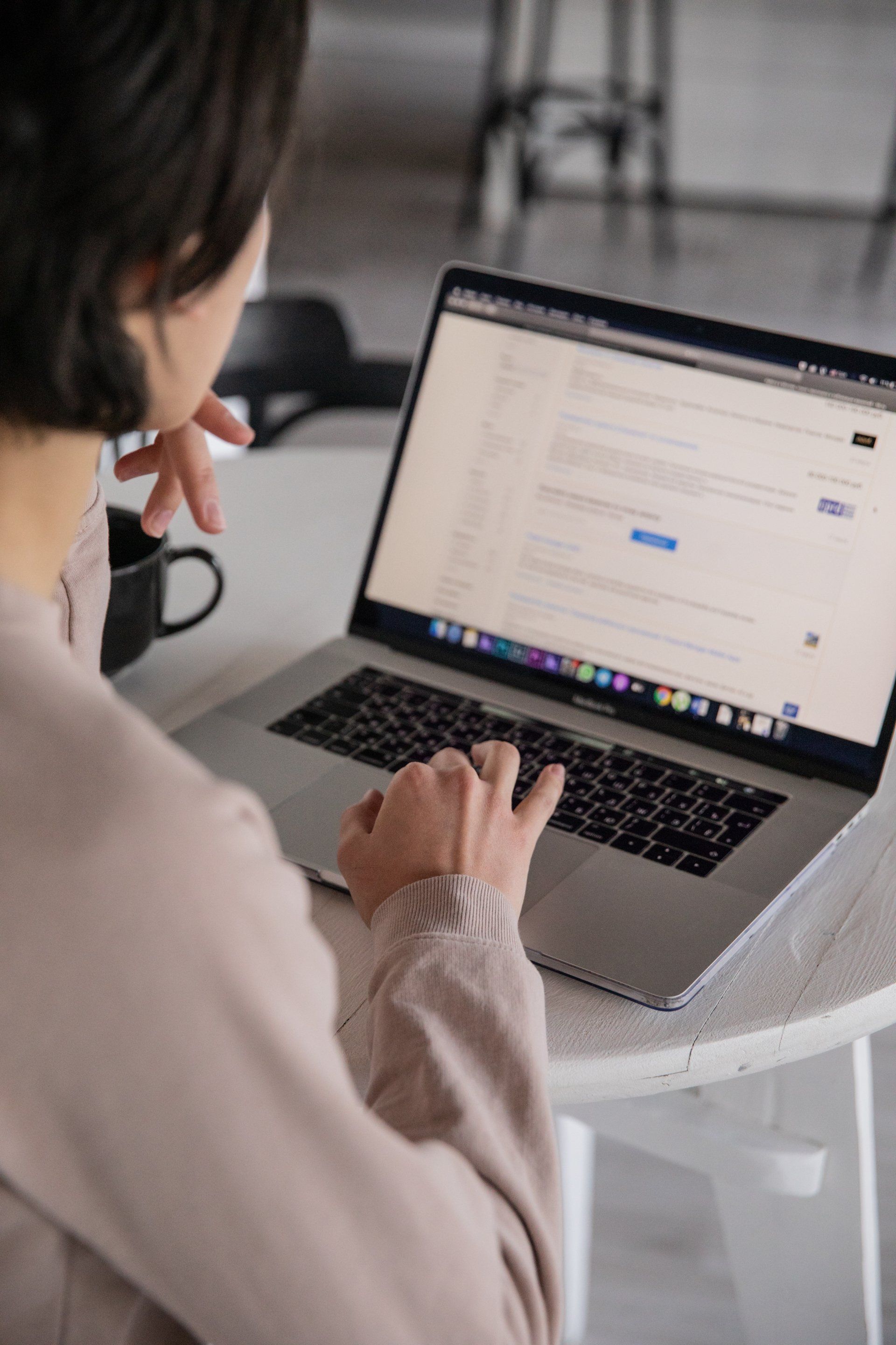 A woman is sitting at a table using a laptop computer.