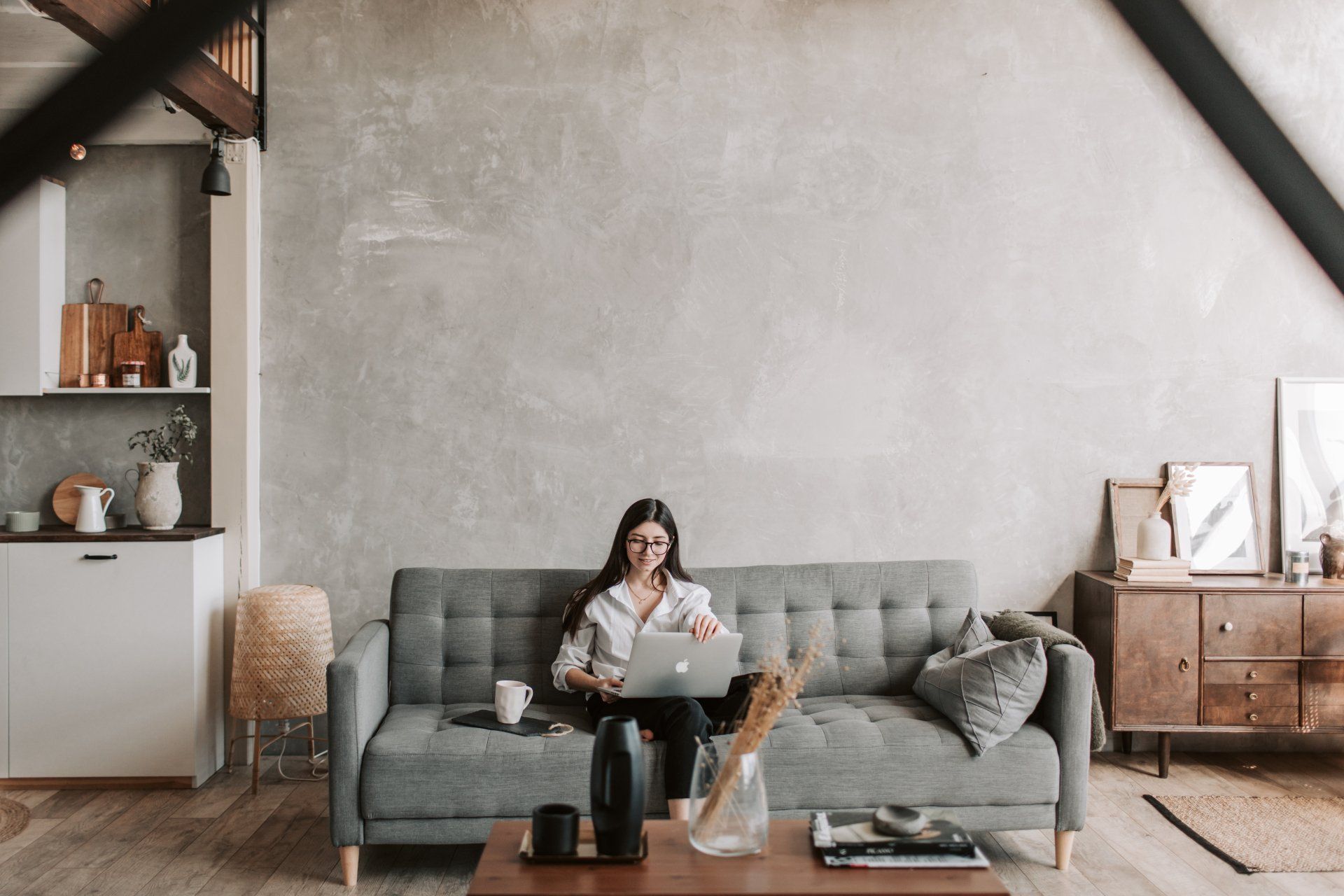 A woman is sitting on a couch using a laptop computer.