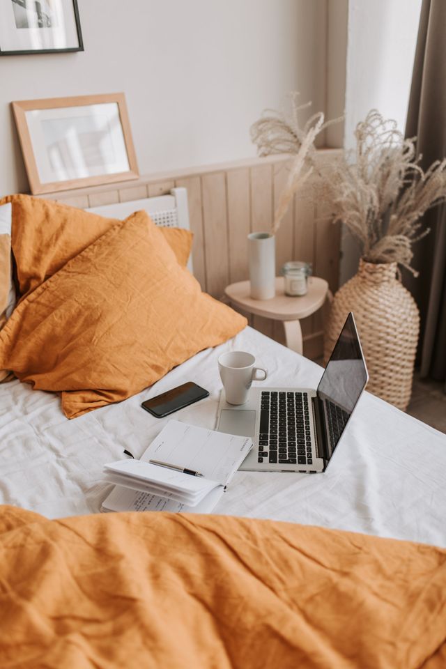 A bed with a laptop and a cup of coffee on it.