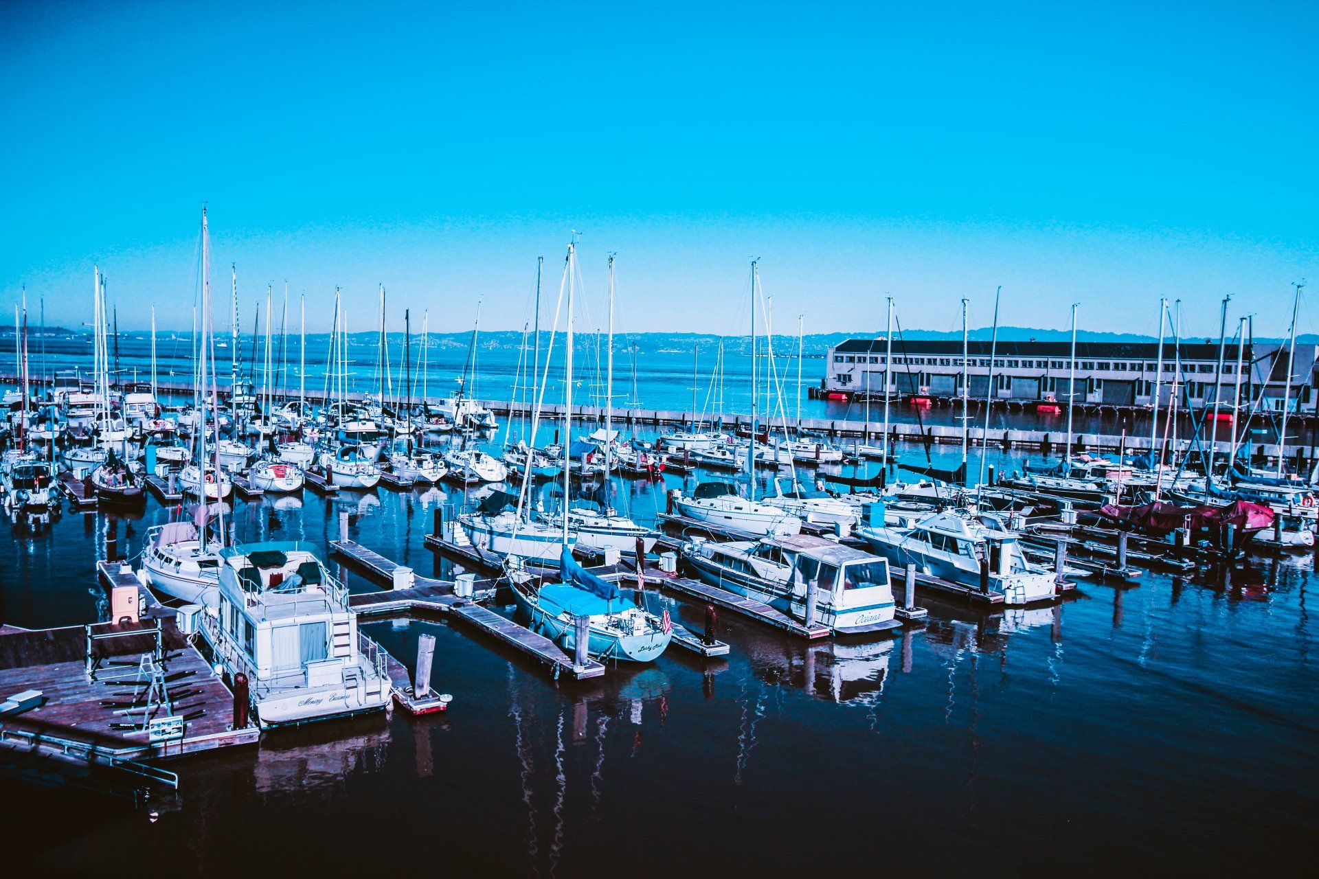 A bunch of boats are docked in a marina on a sunny day.