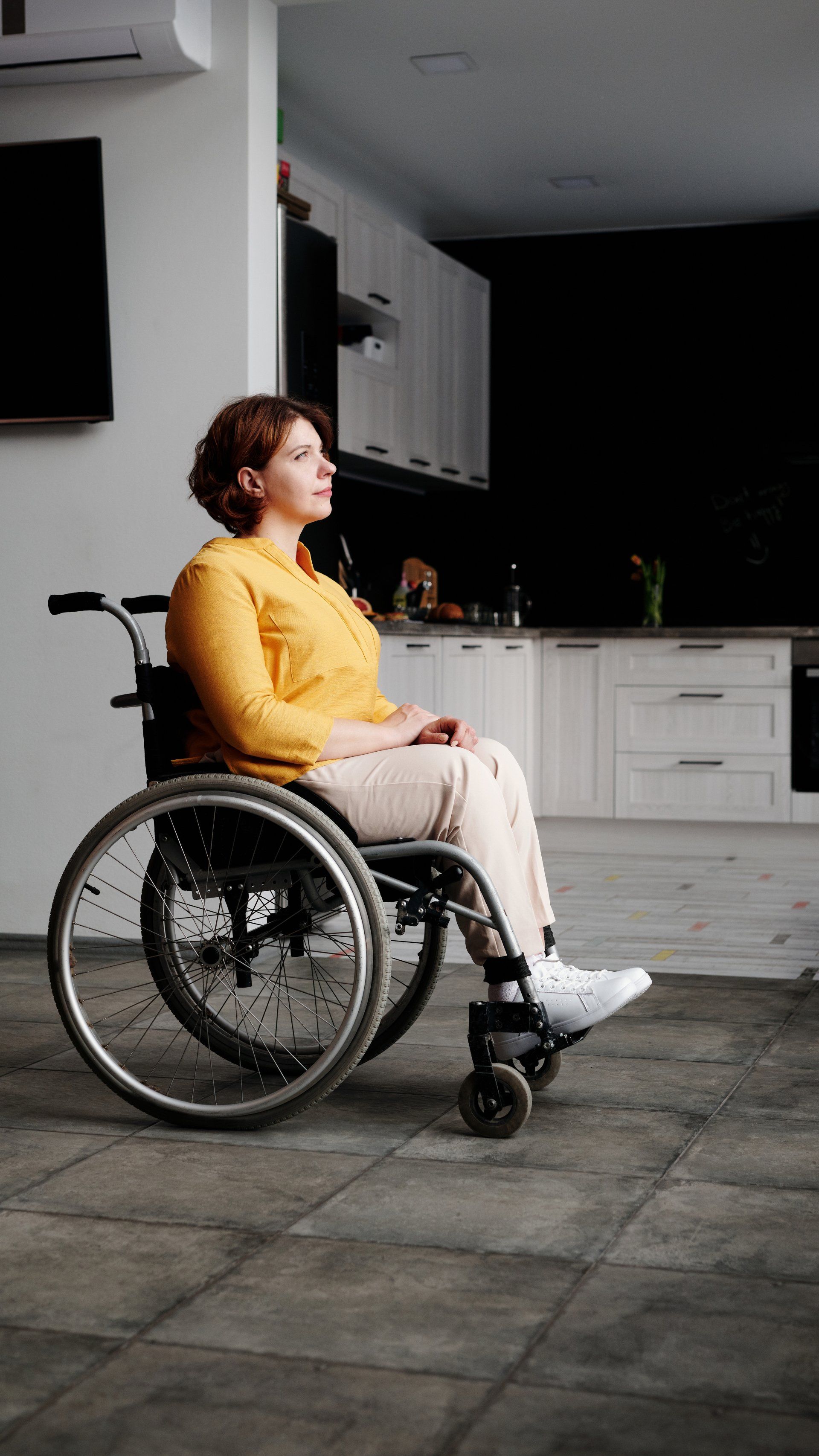 A woman is sitting in a wheelchair in a living room.