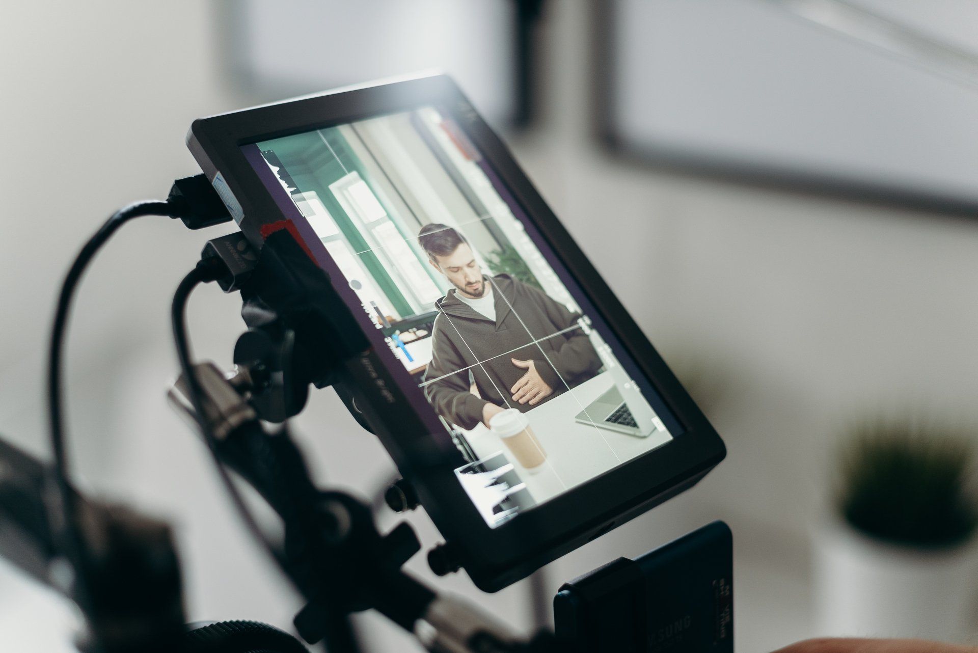 A person is holding a camera with a picture of a man on the screen.