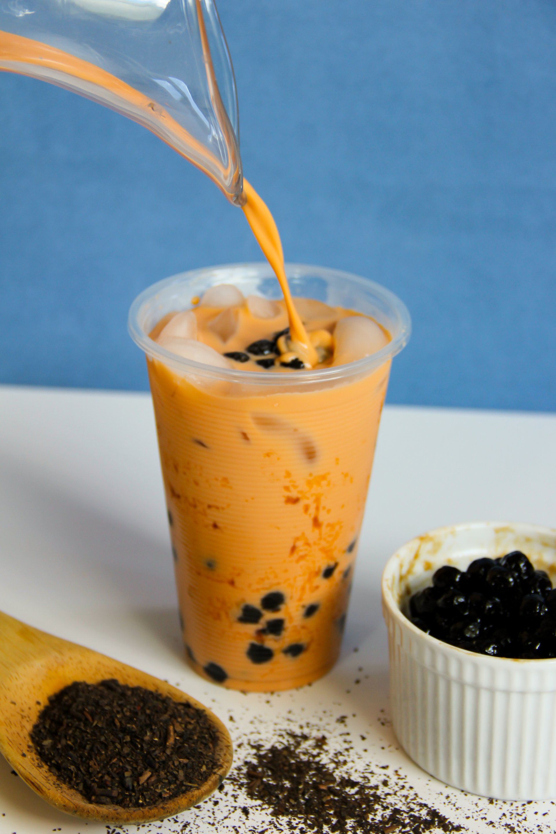 A cup of boba tea is being poured into a plastic cup.