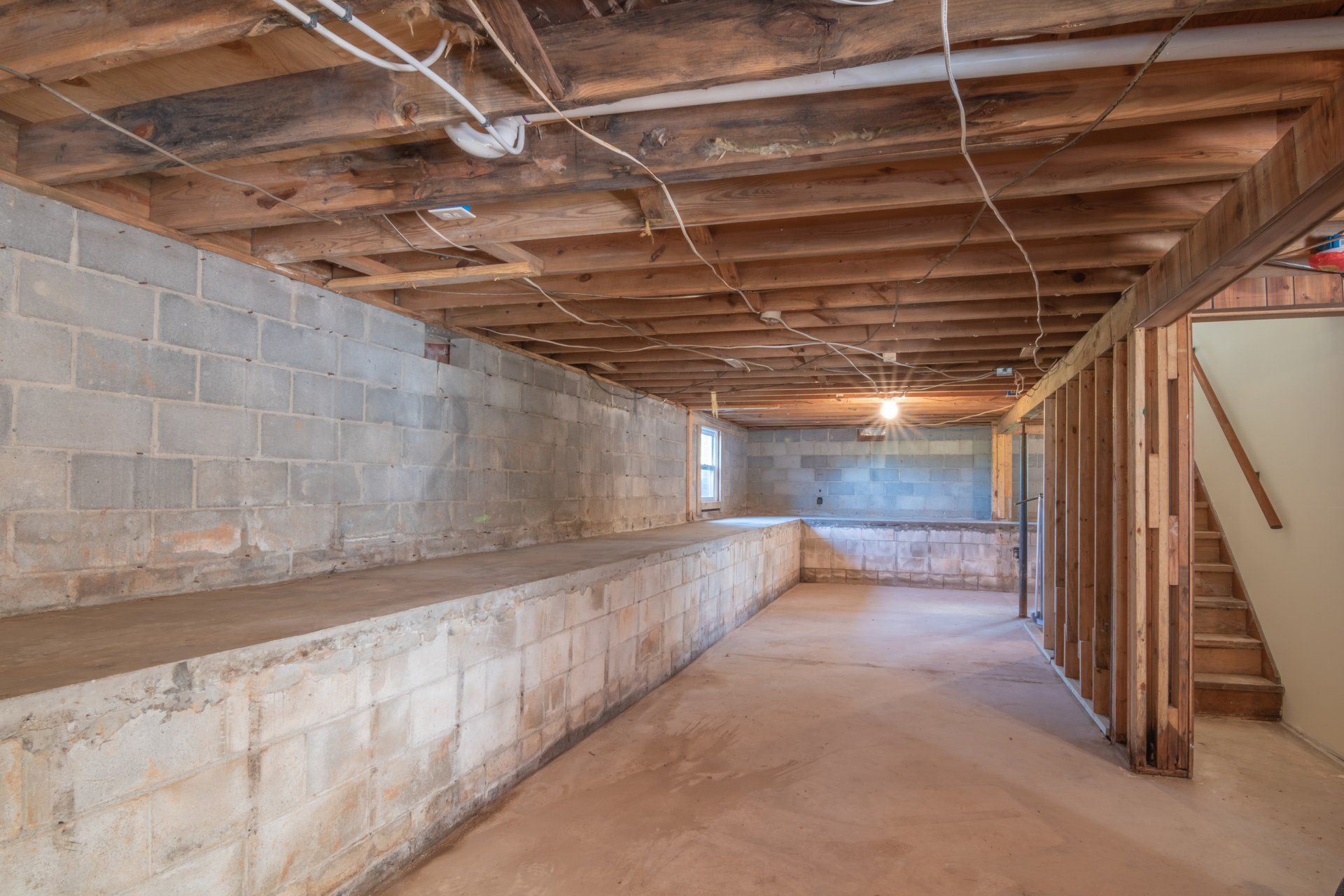 An empty basement with brick walls and wooden beams.