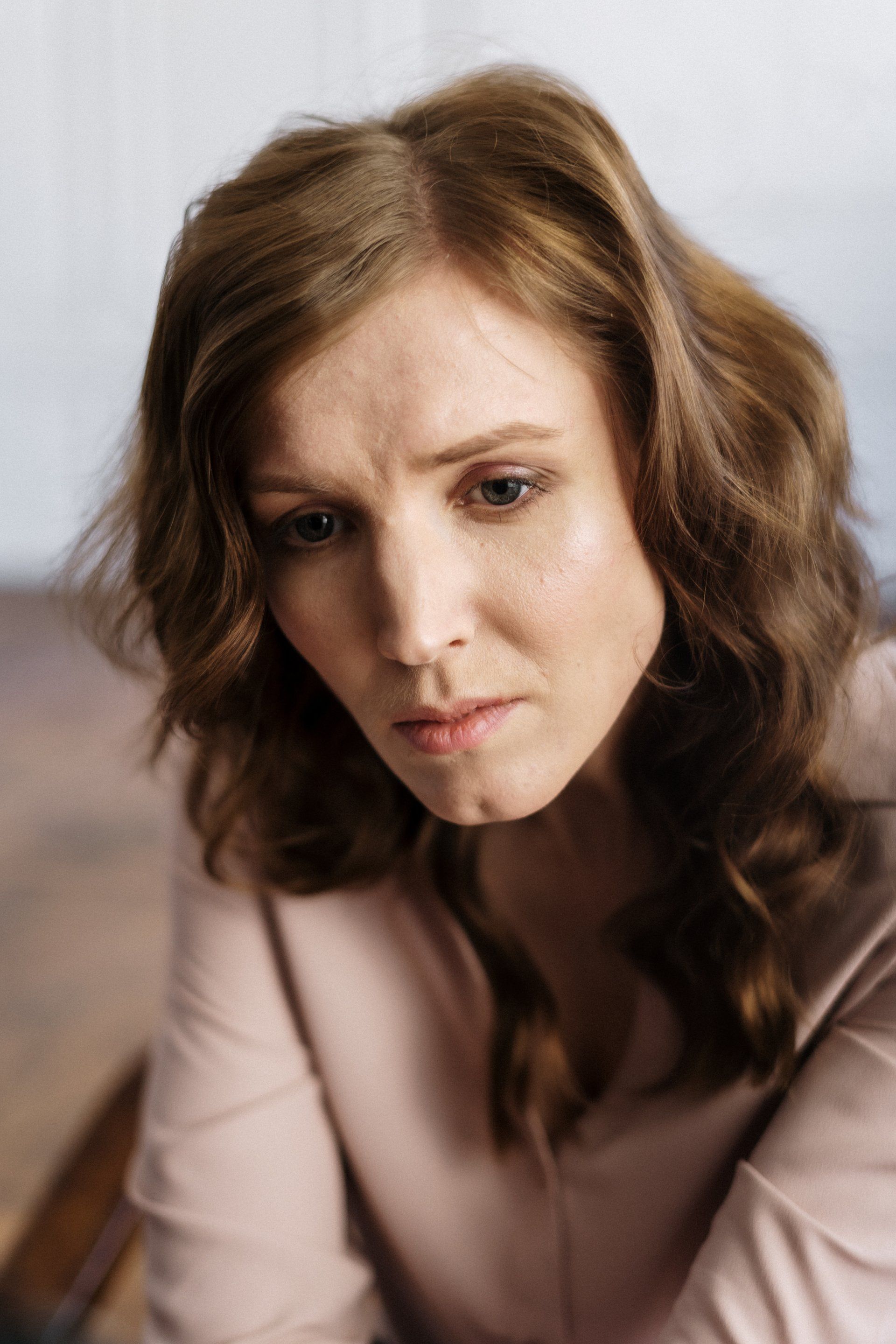 A woman is sitting in a chair with her head down and looking down.