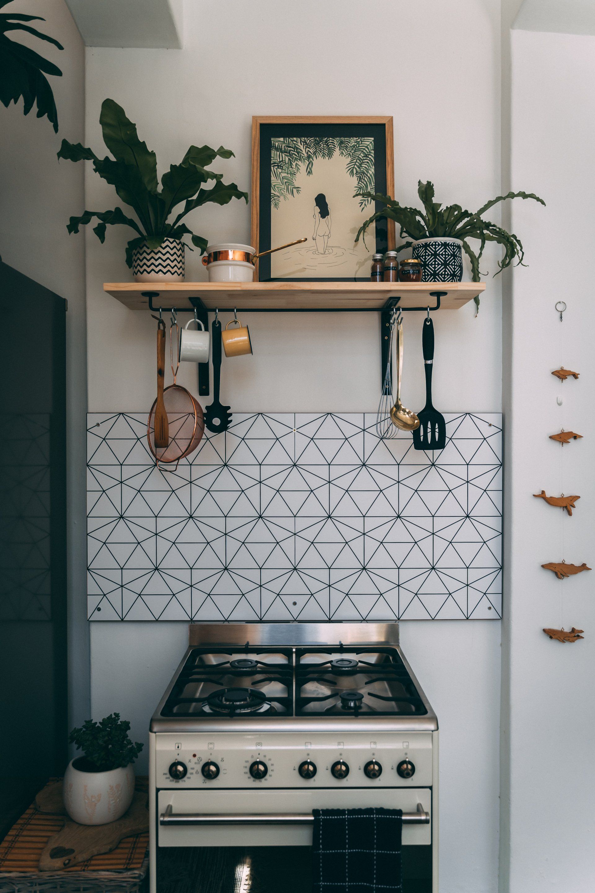 a kitchen with a stove and a shelf with pots and pans on it