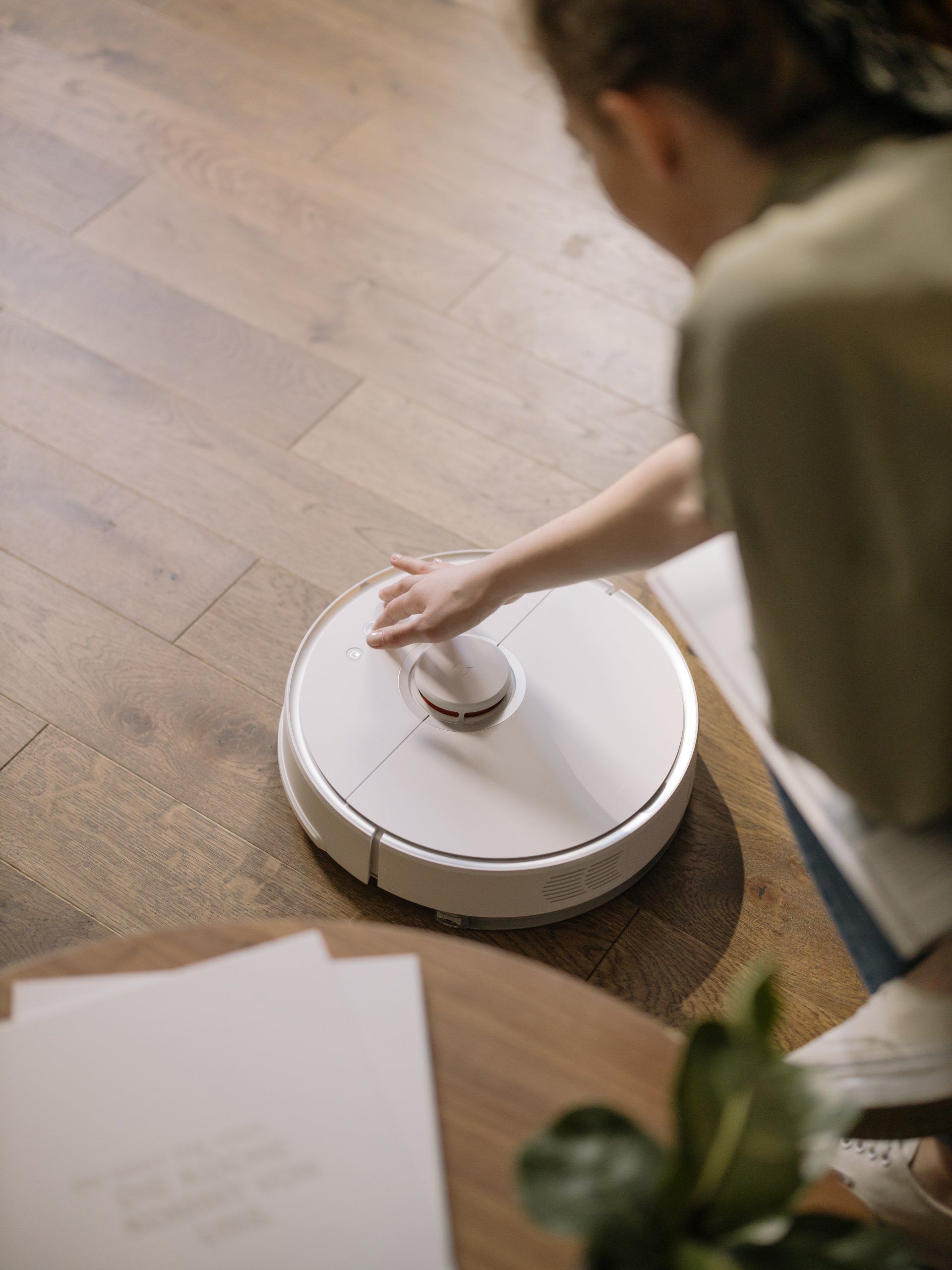 A woman is using a robot vacuum cleaner to clean the floor.