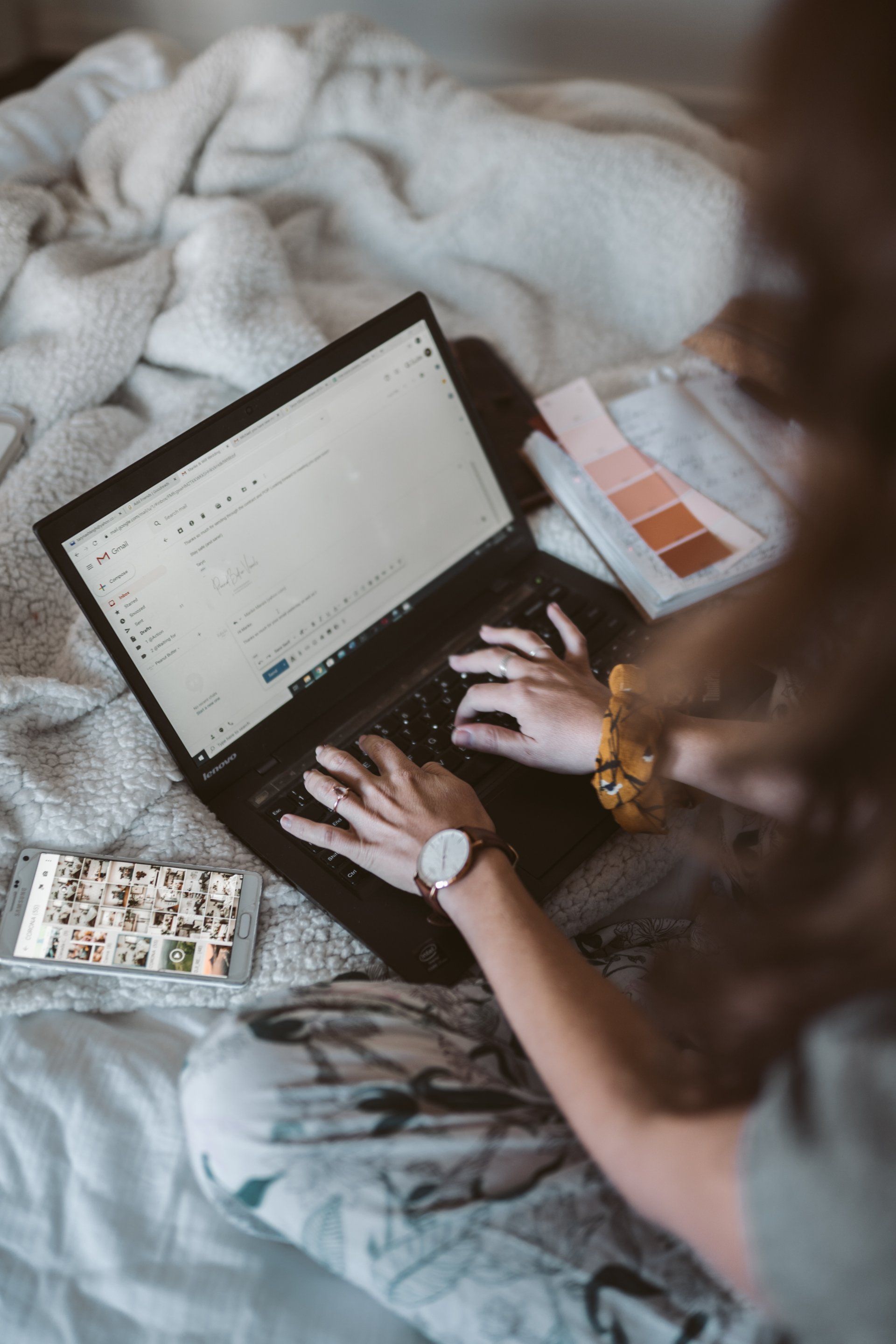 A woman is sitting on a bed using a laptop computer.