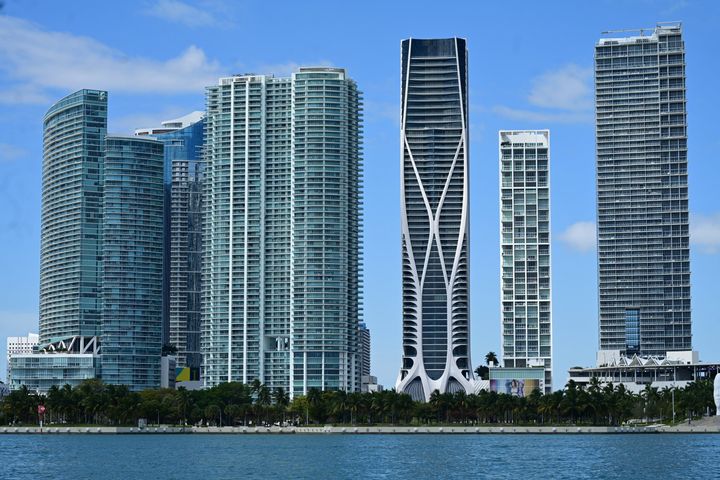 Skyline of modern high-rise buildings in Miami, Florida, with a clear blue sky and water in the foreground.