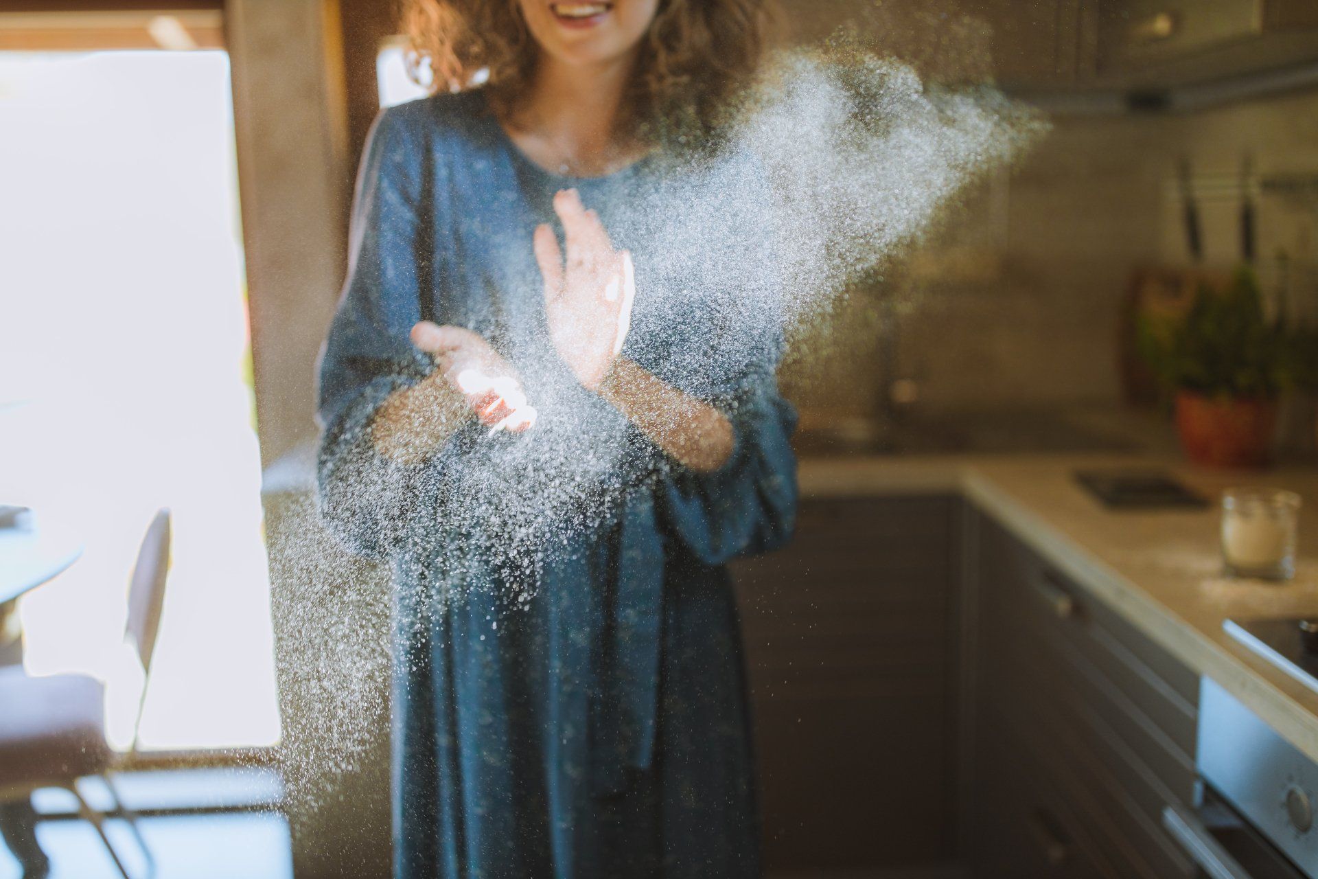 A woman in a blue dress is throwing flour in the air