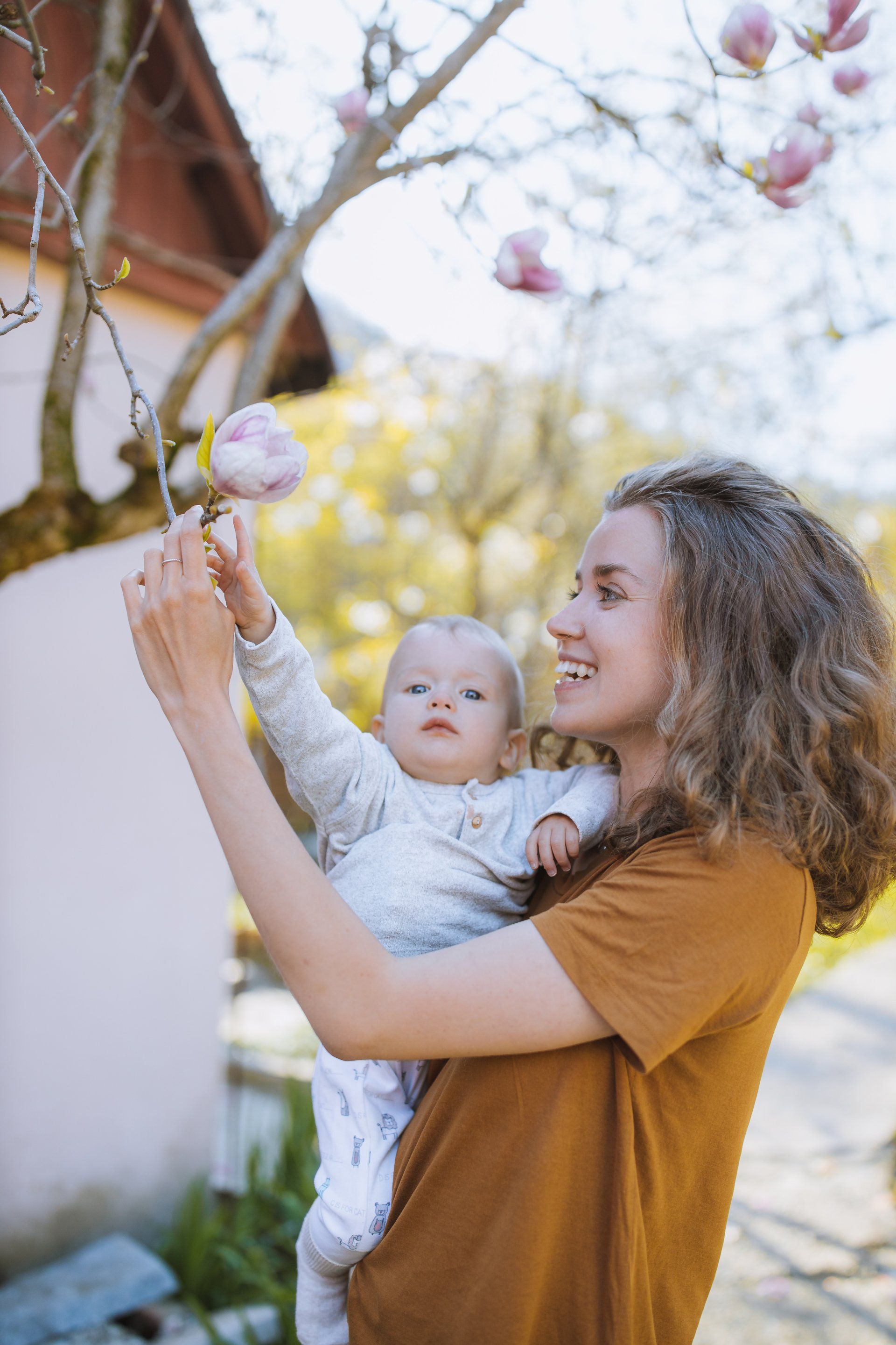 Eine Frau hält ein Baby und betrachtet eine Blume auf einem Baum.