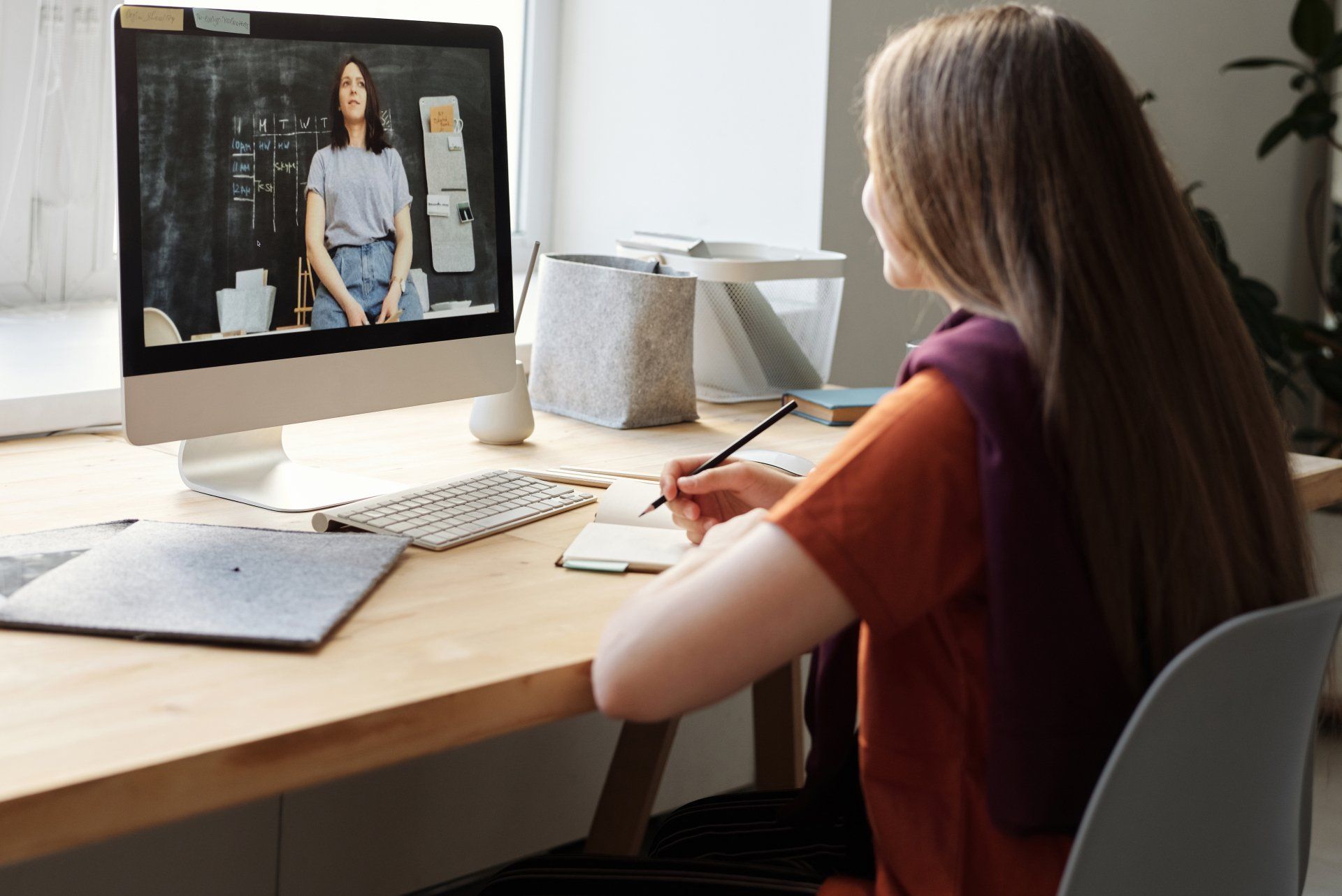 A woman is sitting at a desk looking at a computer screen.