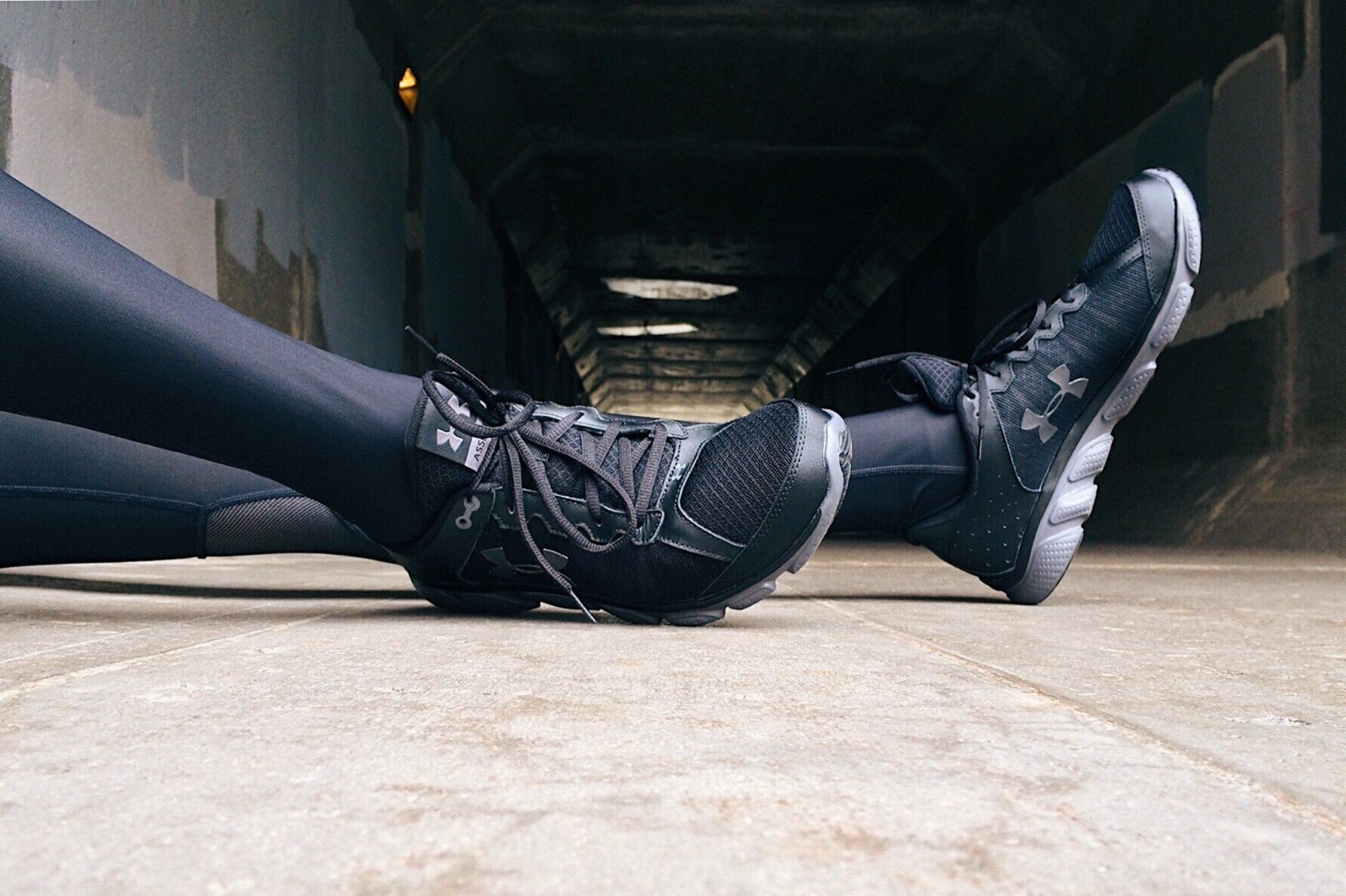A person is laying on the ground wearing a pair of under armour shoes.