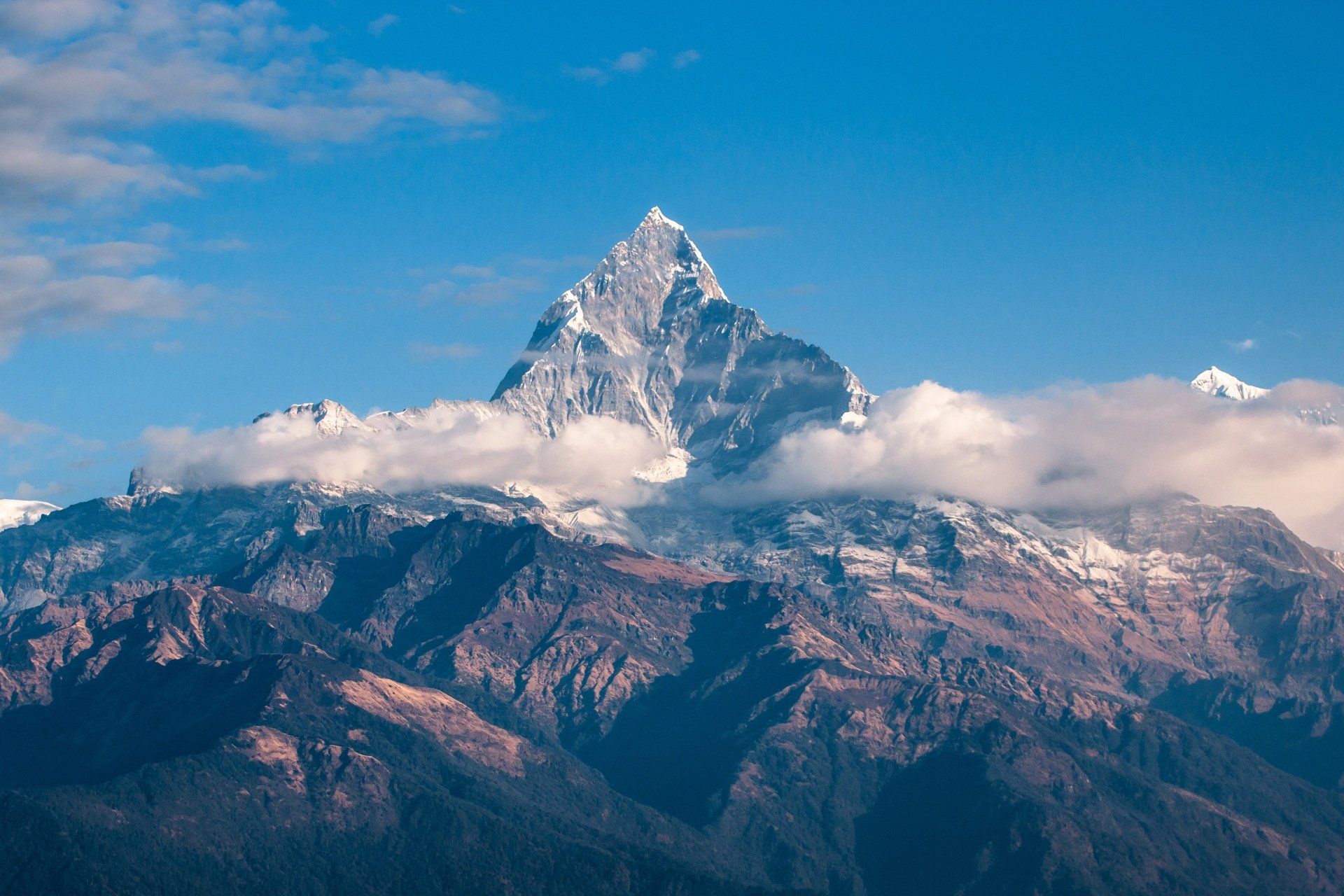 A mountain covered in snow and clouds with a blue sky in the background.