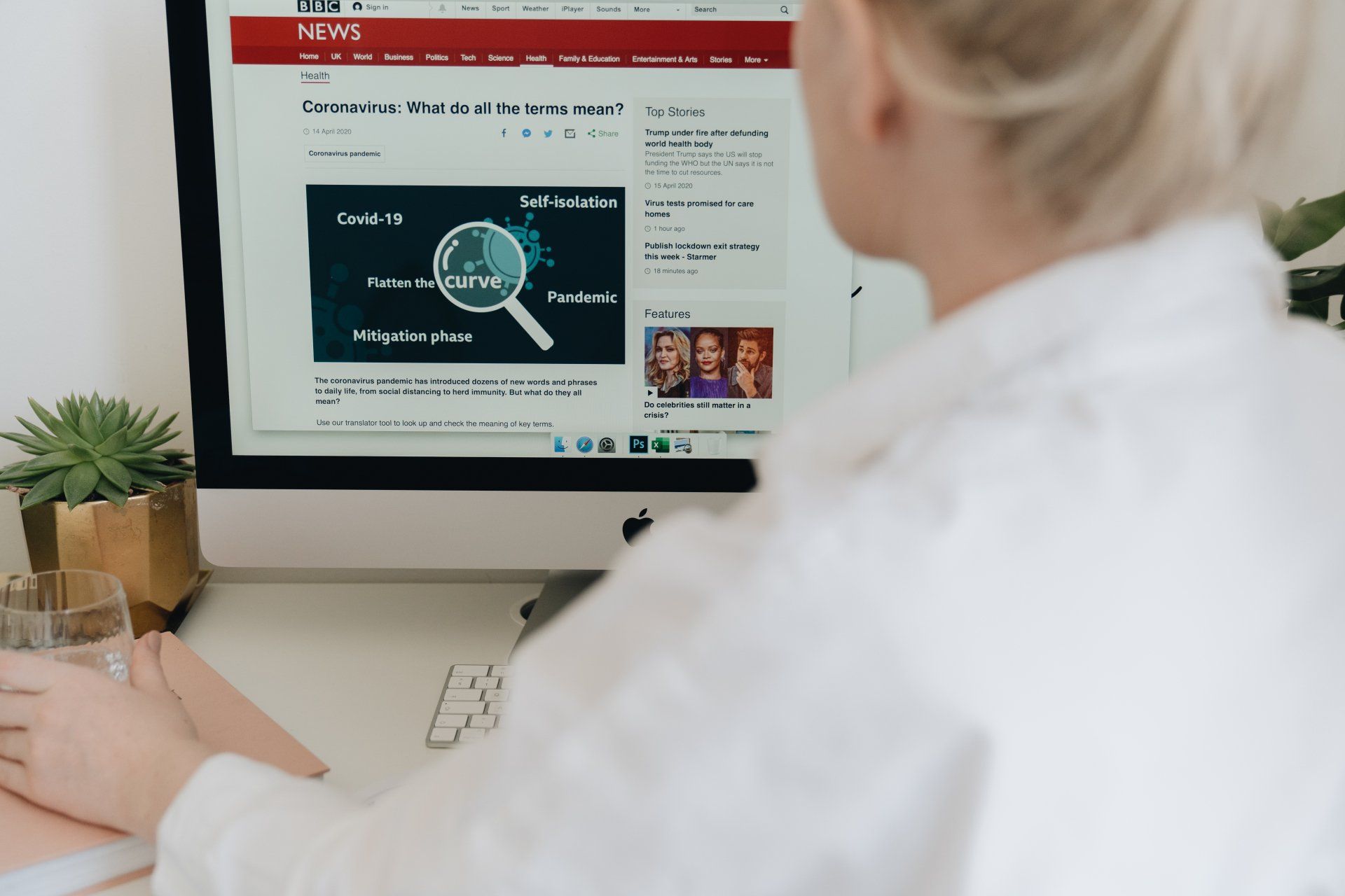 A woman is sitting at a desk looking at a computer screen.